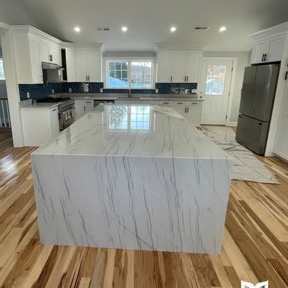 A kitchen with a large island and hardwood floors.