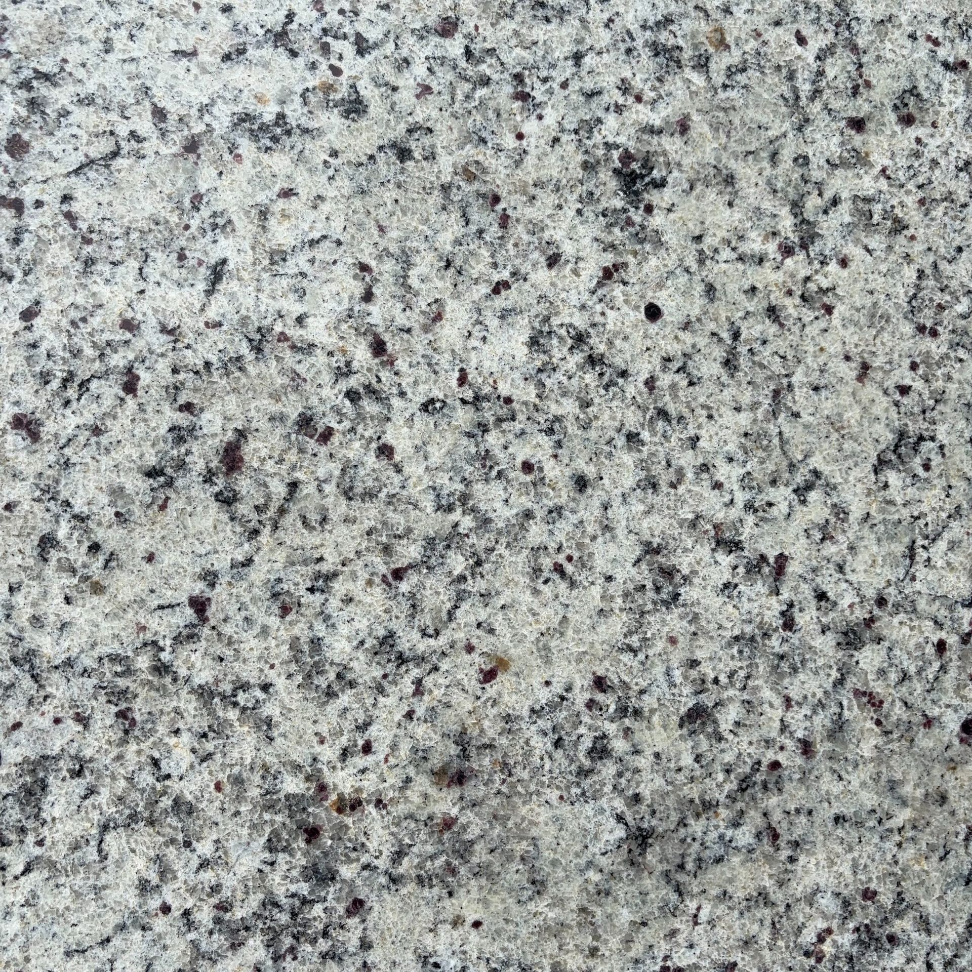 A close up of a white granite counter top with black spots.