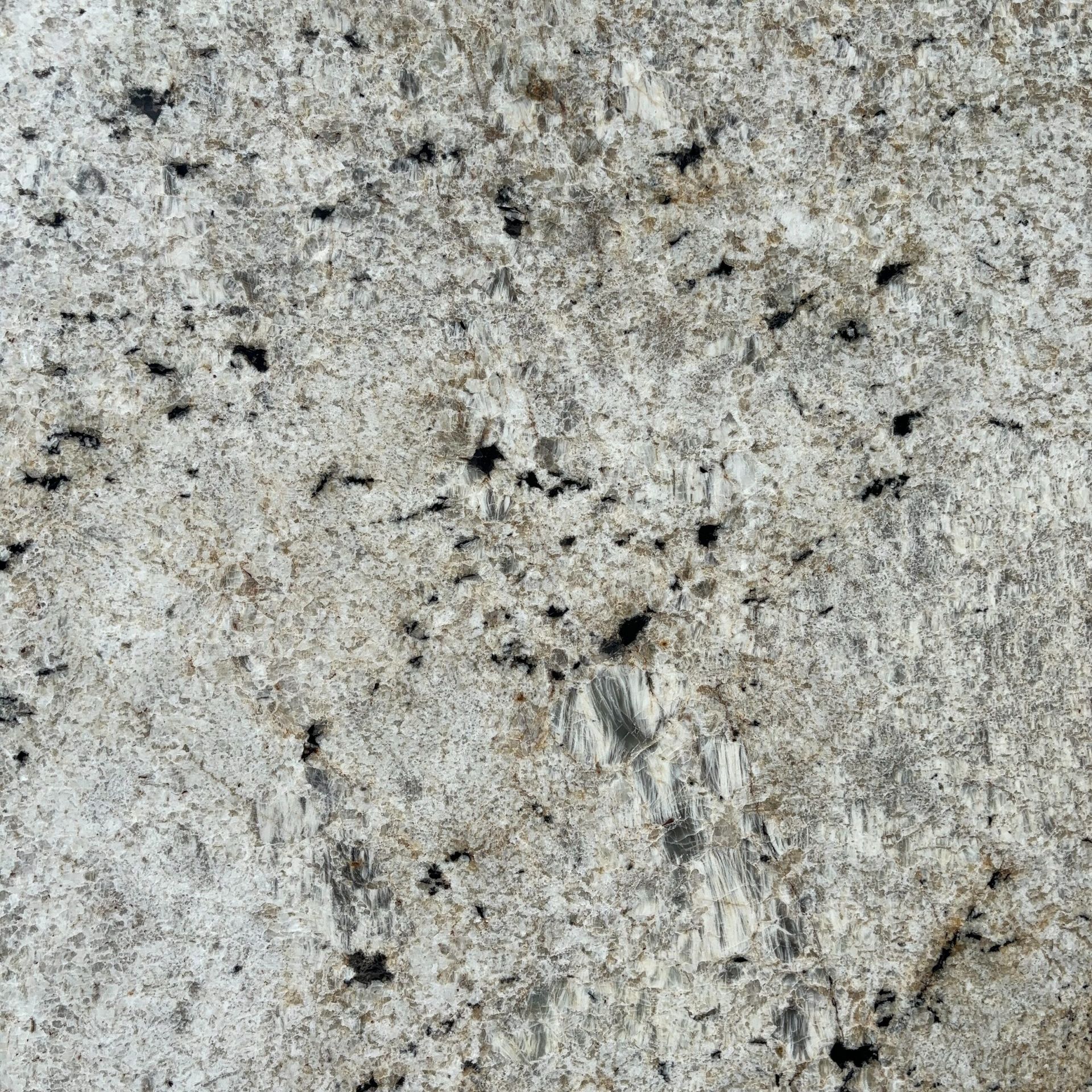 A close up of a white granite counter top with black spots.