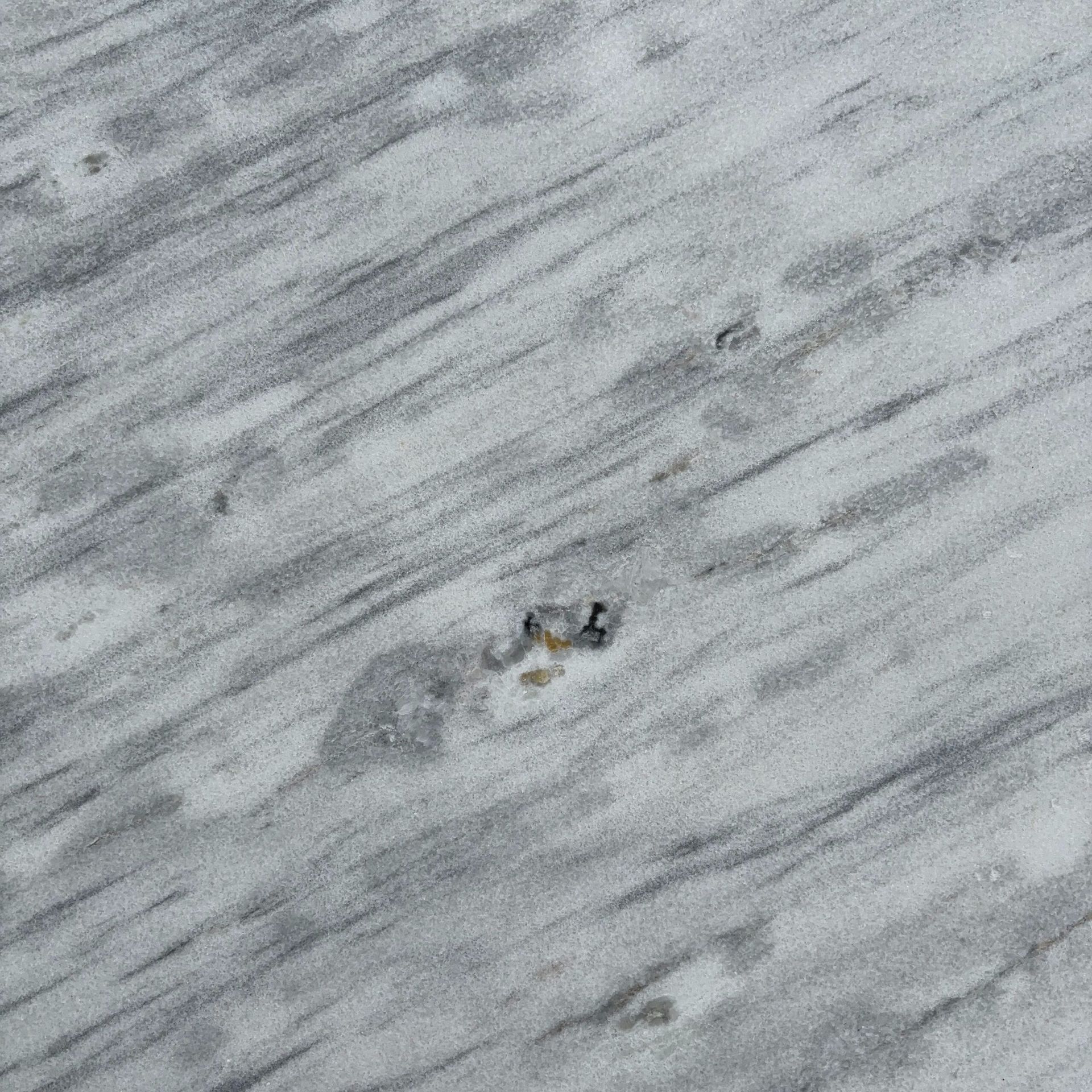 A large piece of granite is sitting on the ground next to a tree.