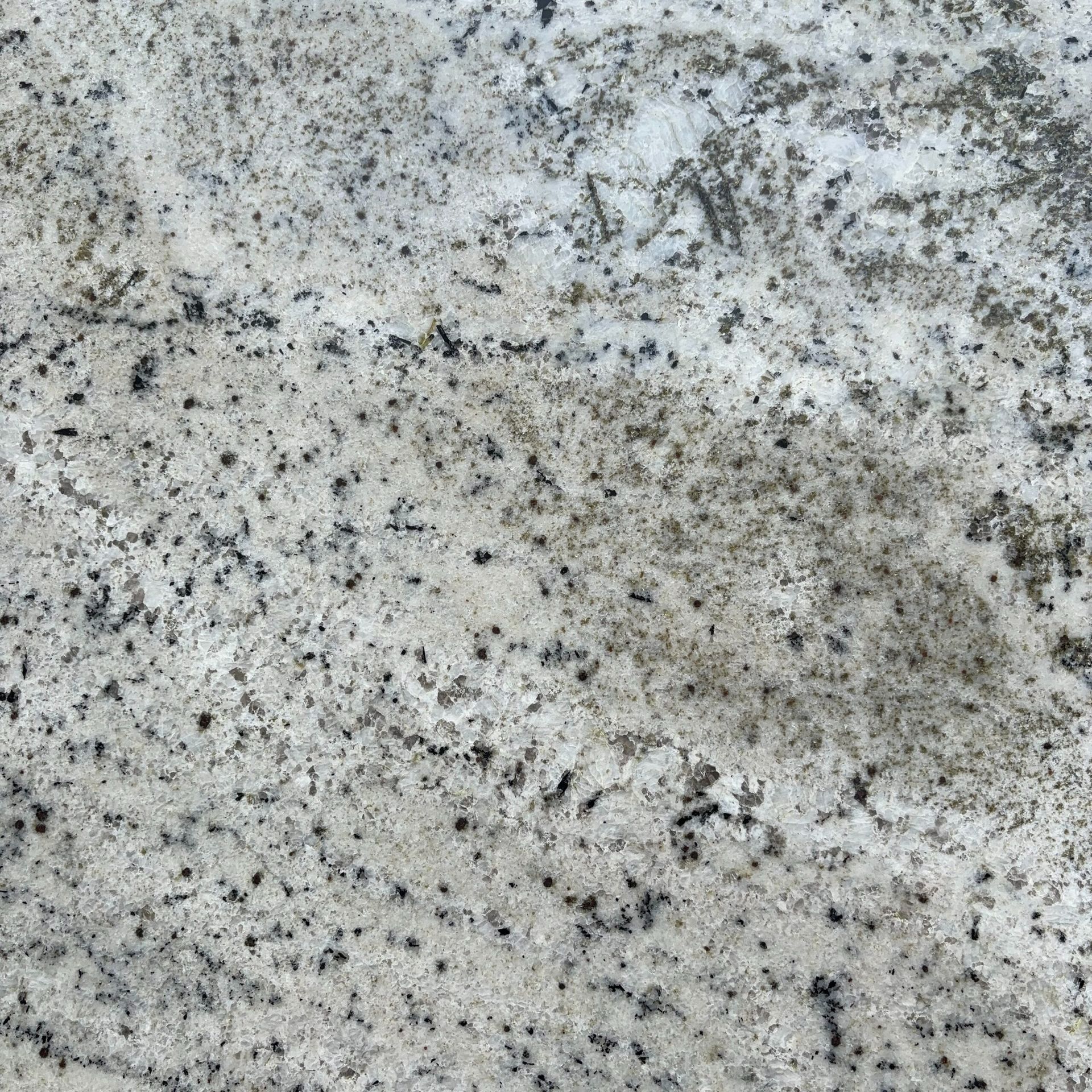 A close up of a white granite counter top with black spots.