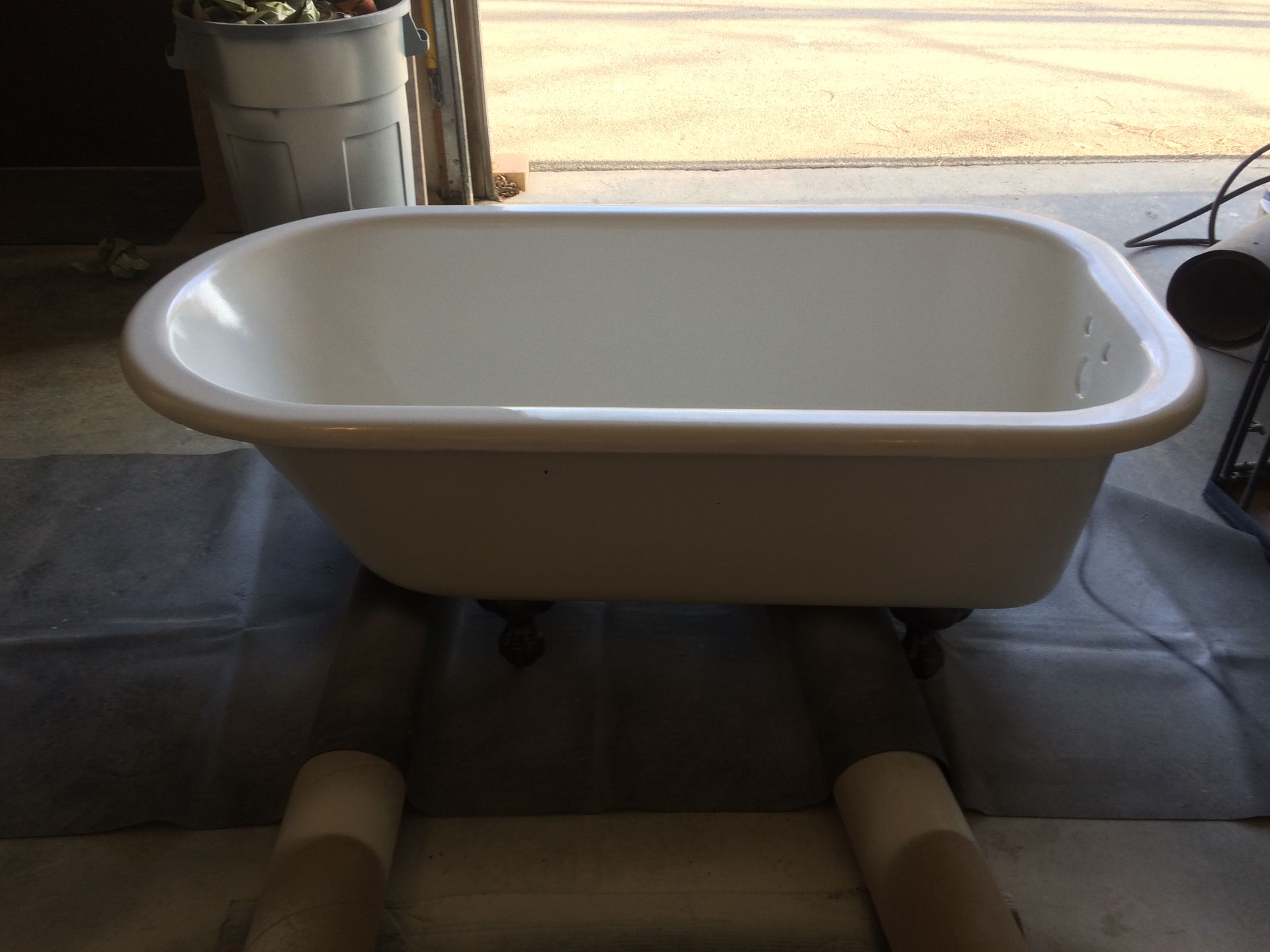 A white bathtub is sitting on top of some cardboard rolls
