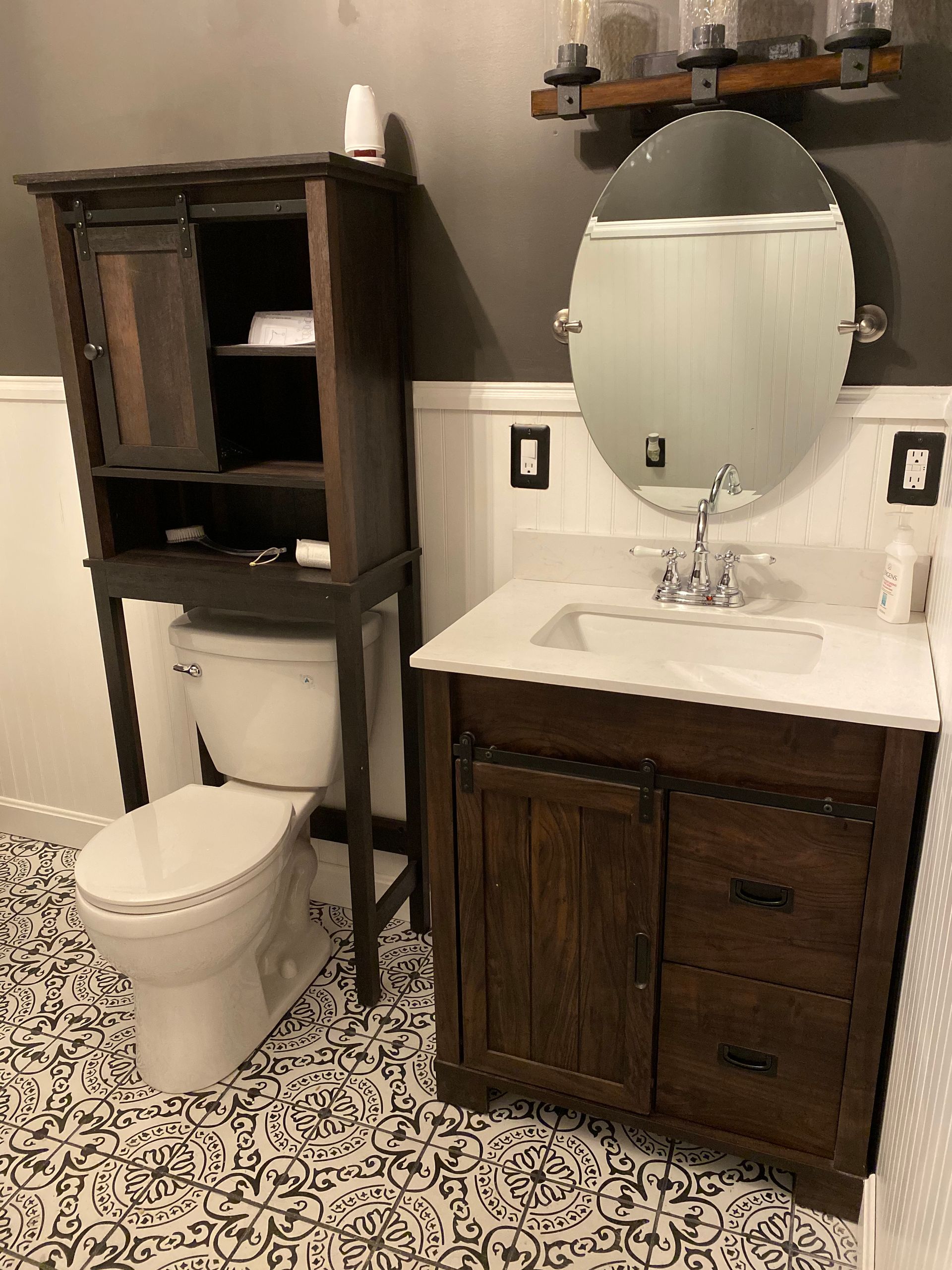 A bathroom with a toilet, sink, mirror and cabinet