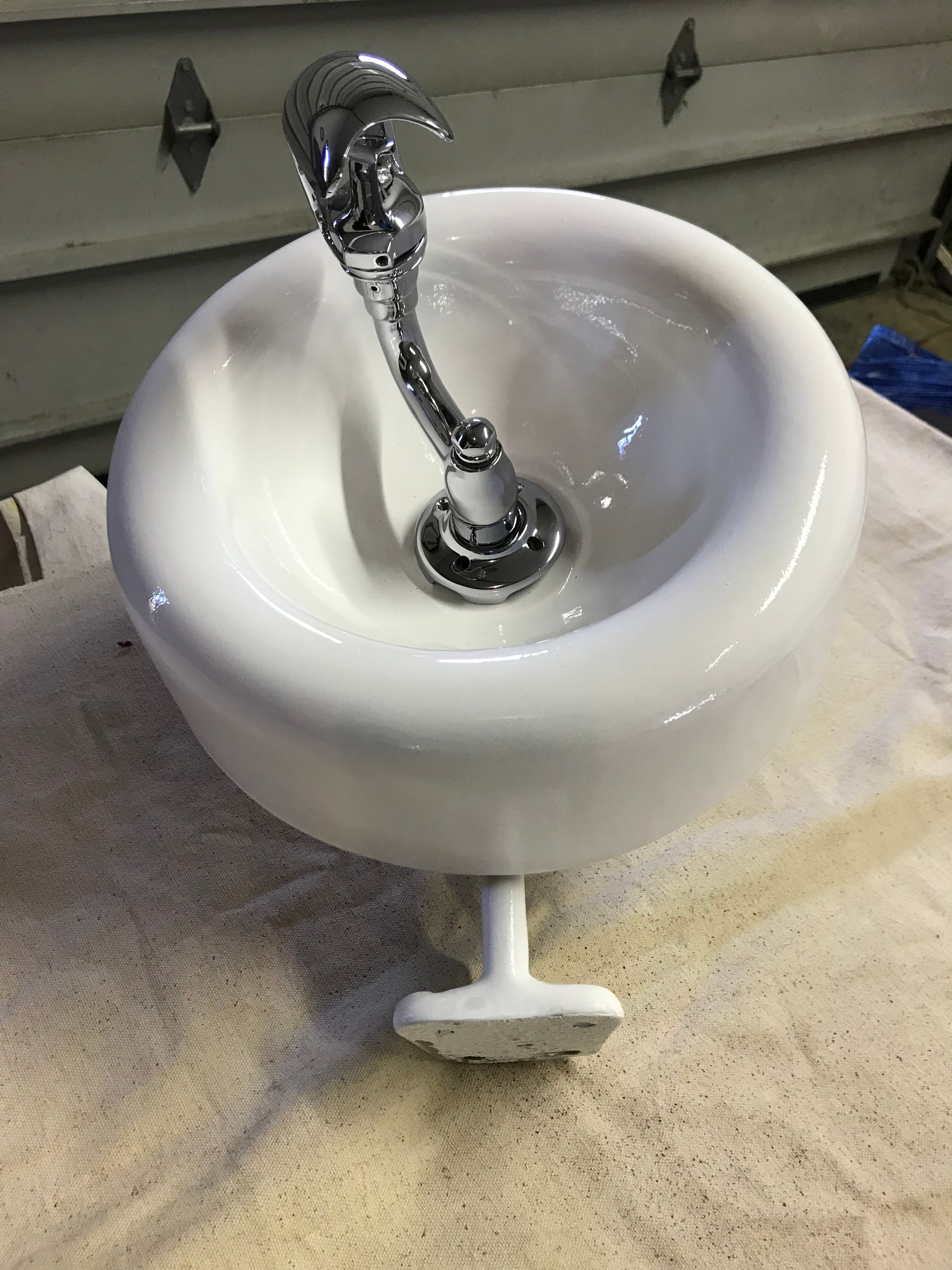 A white sink with a chrome faucet is sitting on a towel
