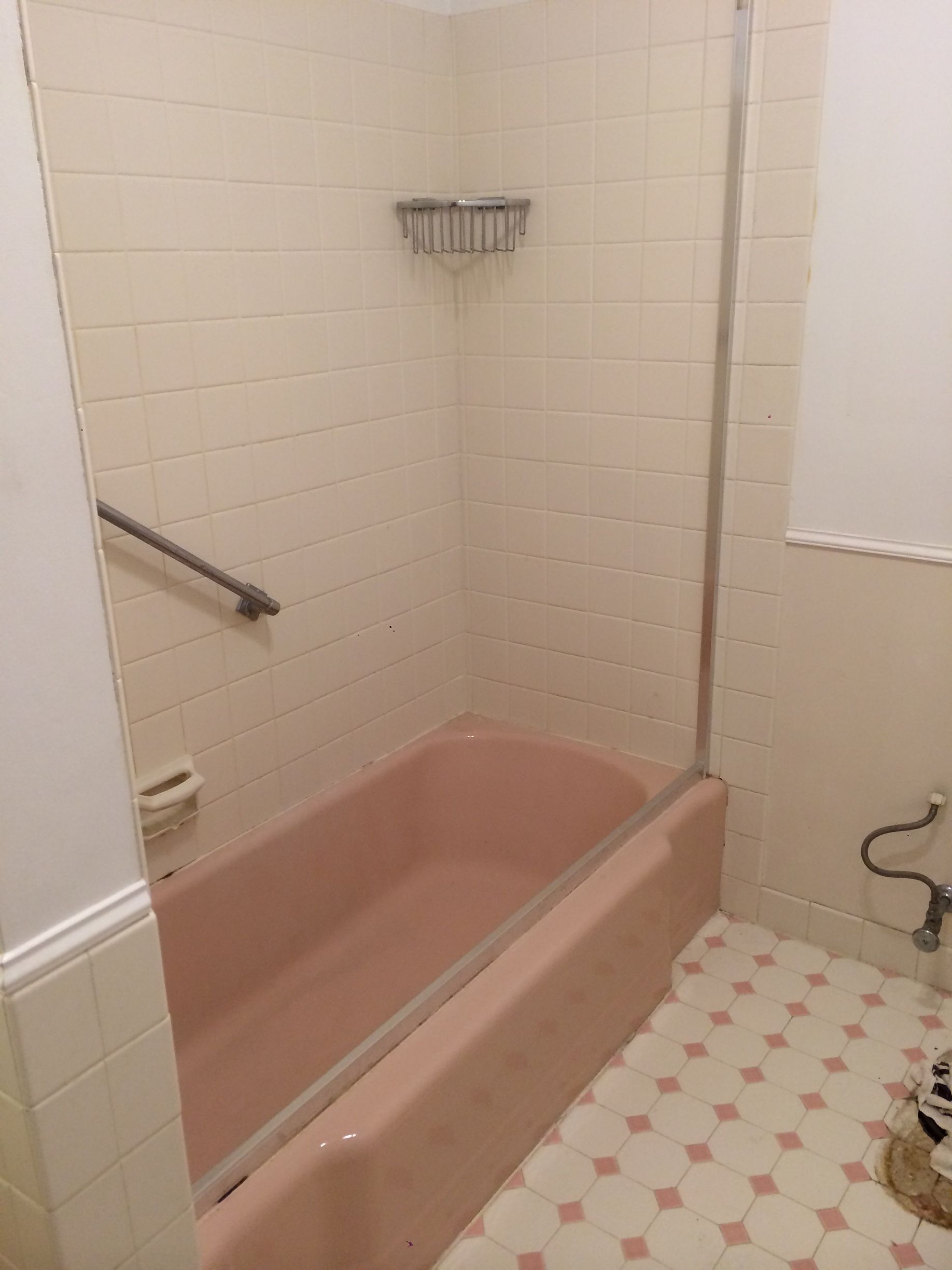 A bathroom with a pink bathtub and a shower stall