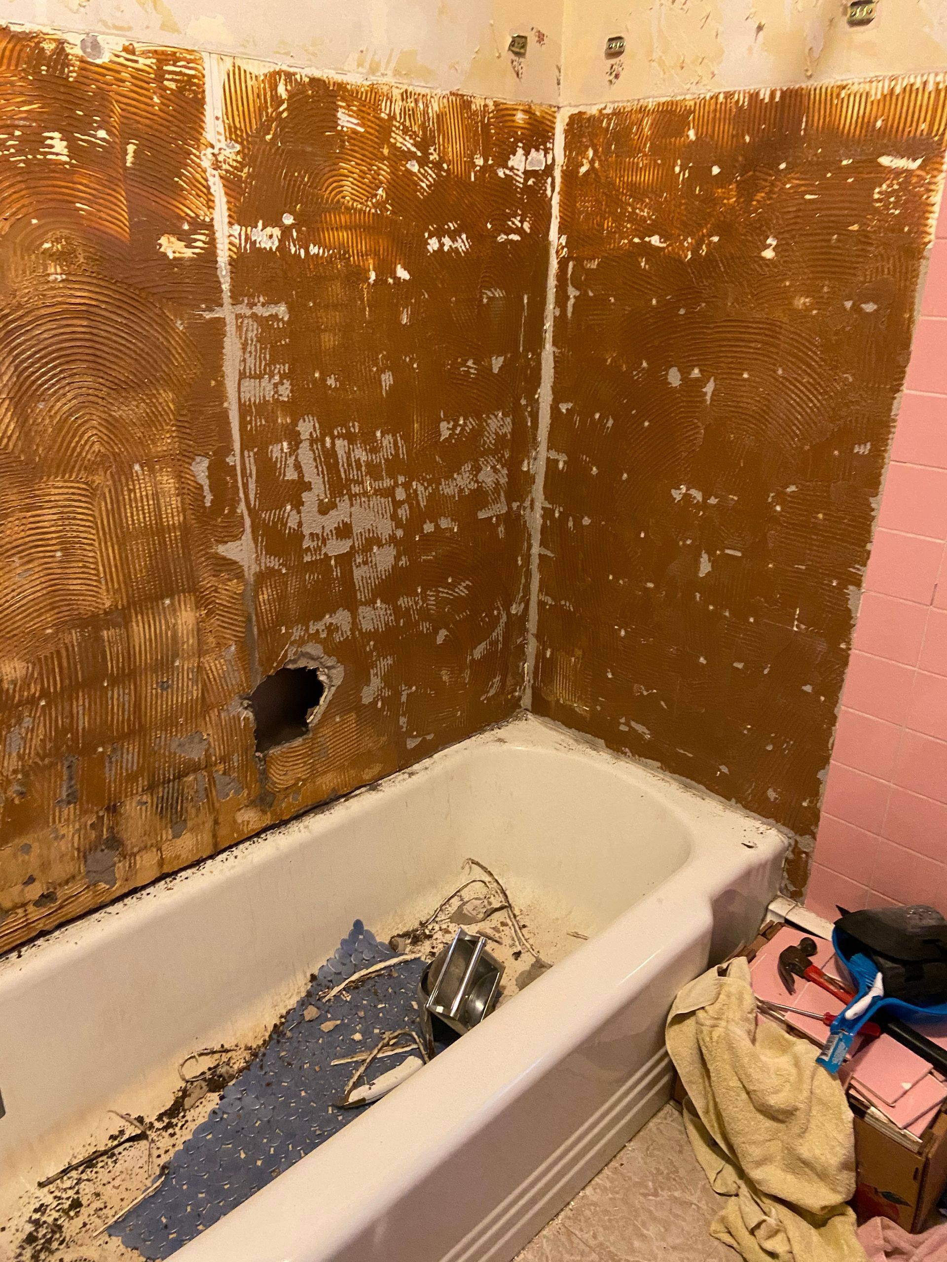 A bathtub in a bathroom with a hole in the wall