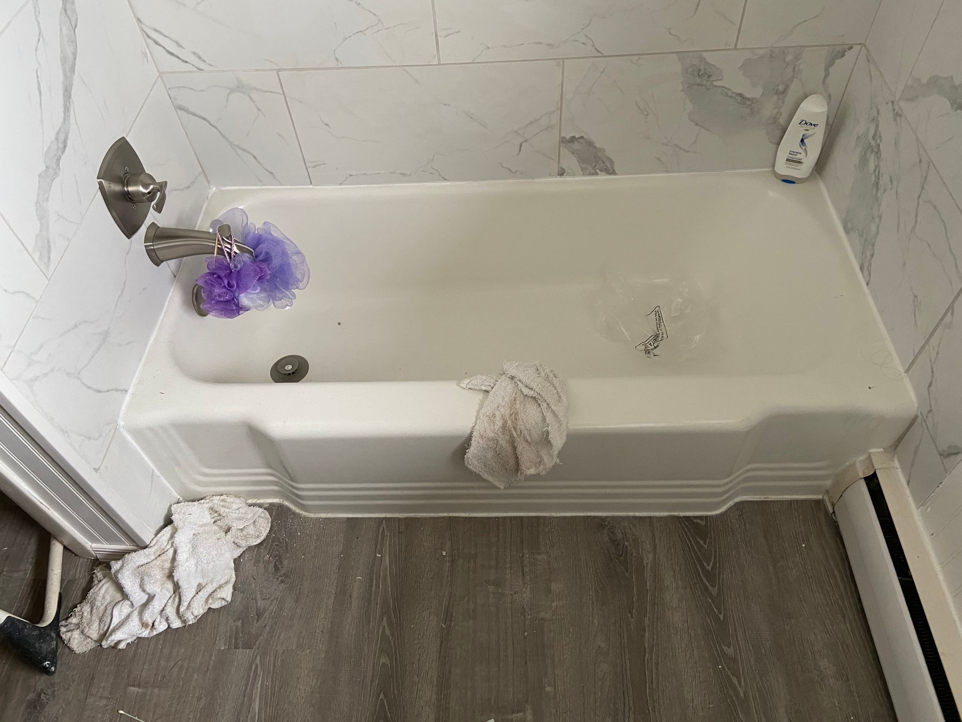 A bathtub in a bathroom with a purple sponge in it