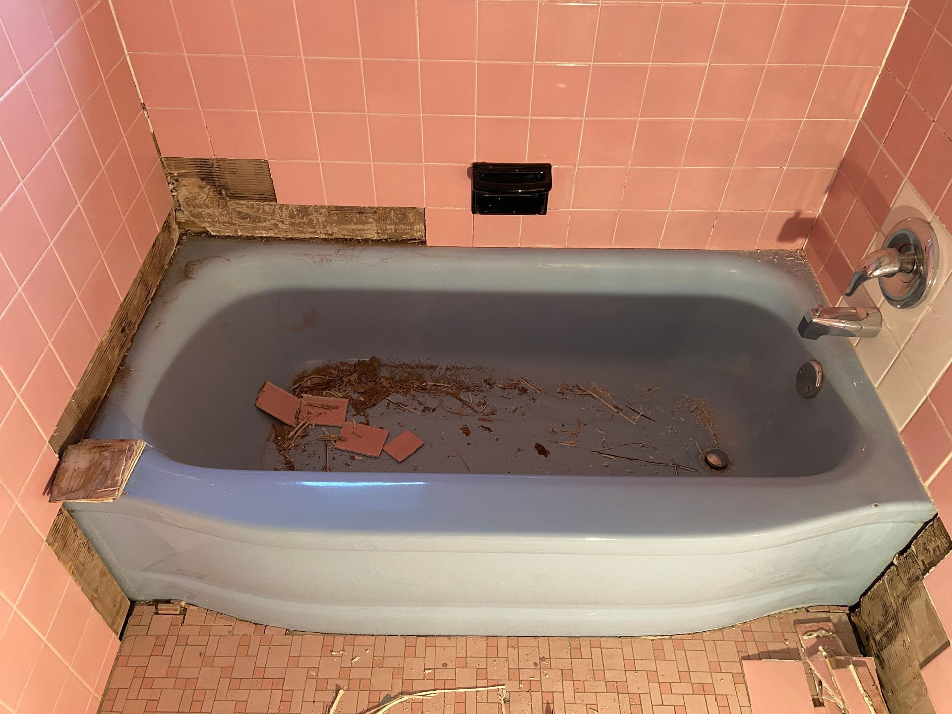A blue bathtub in a bathroom with pink tiles