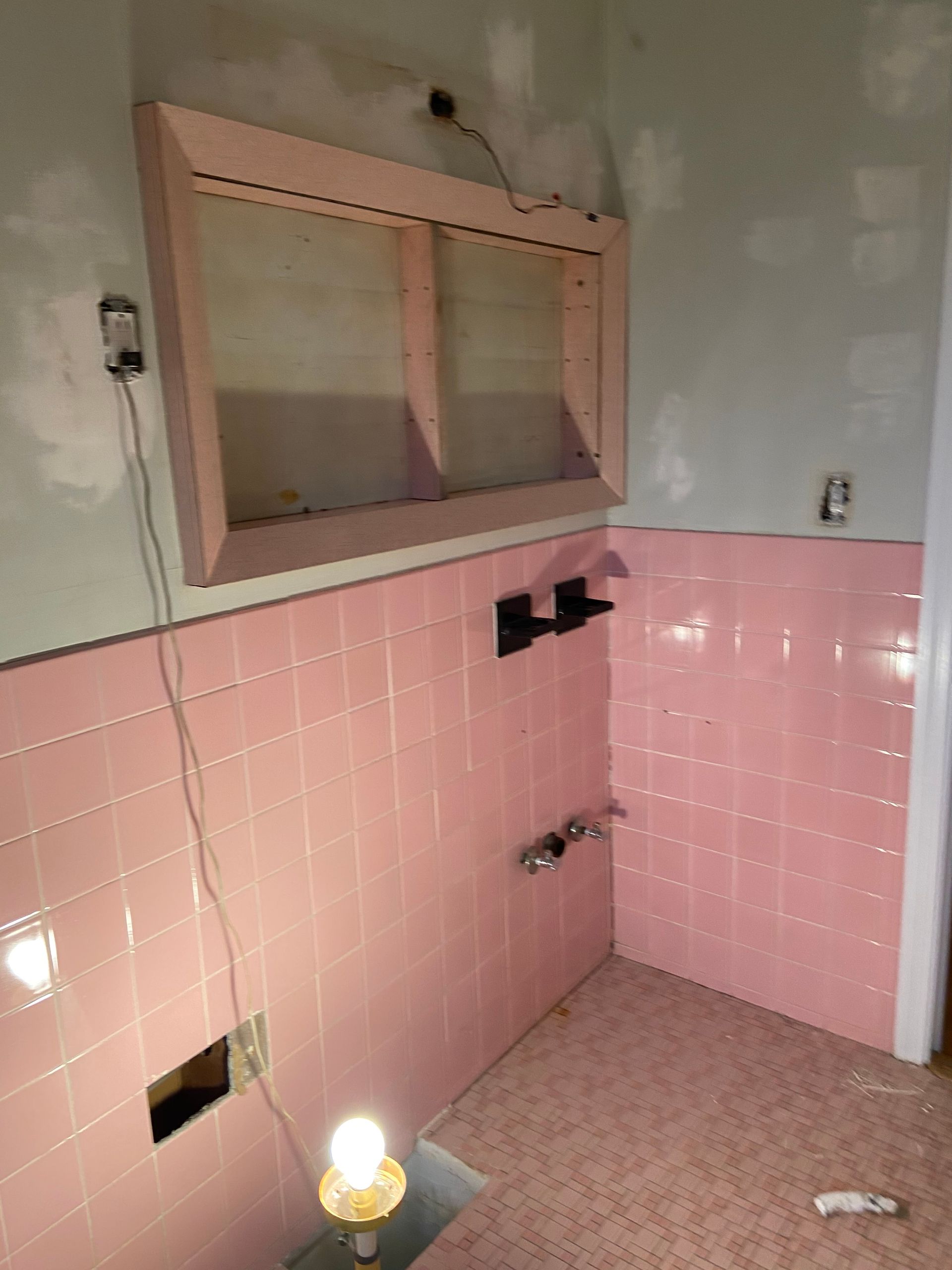 A bathroom with pink tiles and a mirror