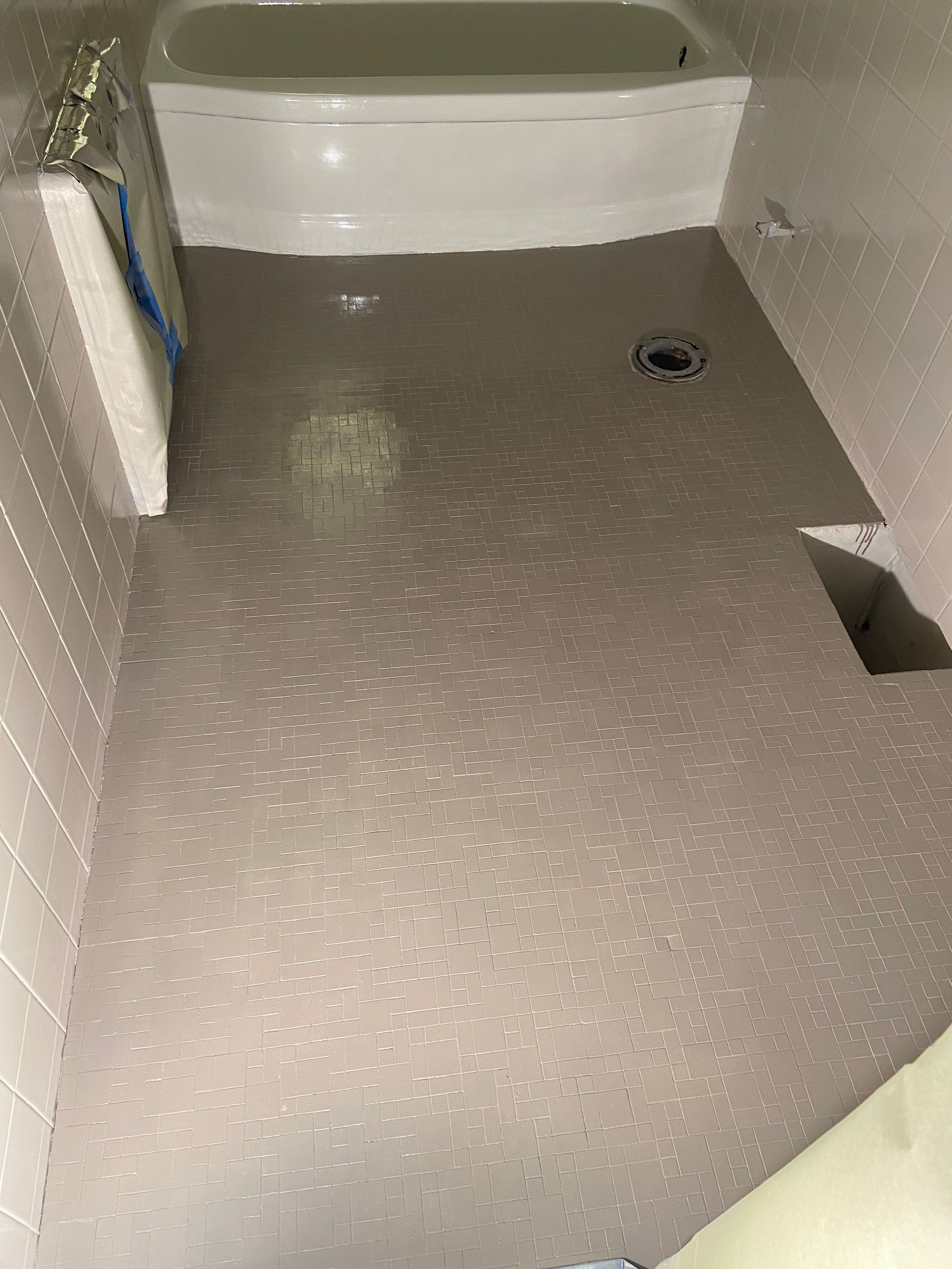 A bathroom with a bathtub and a drain on the floor