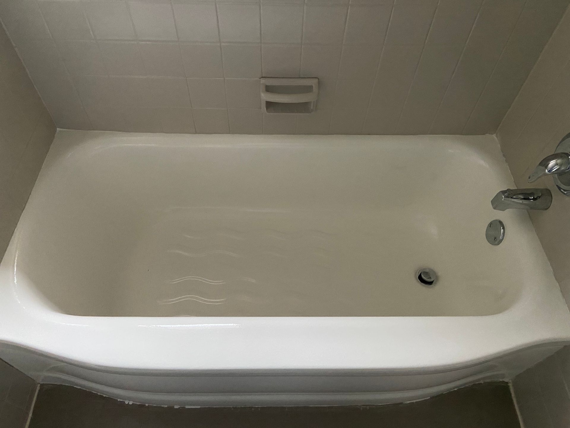 A white bathtub in a bathroom with a soap dish on the wall