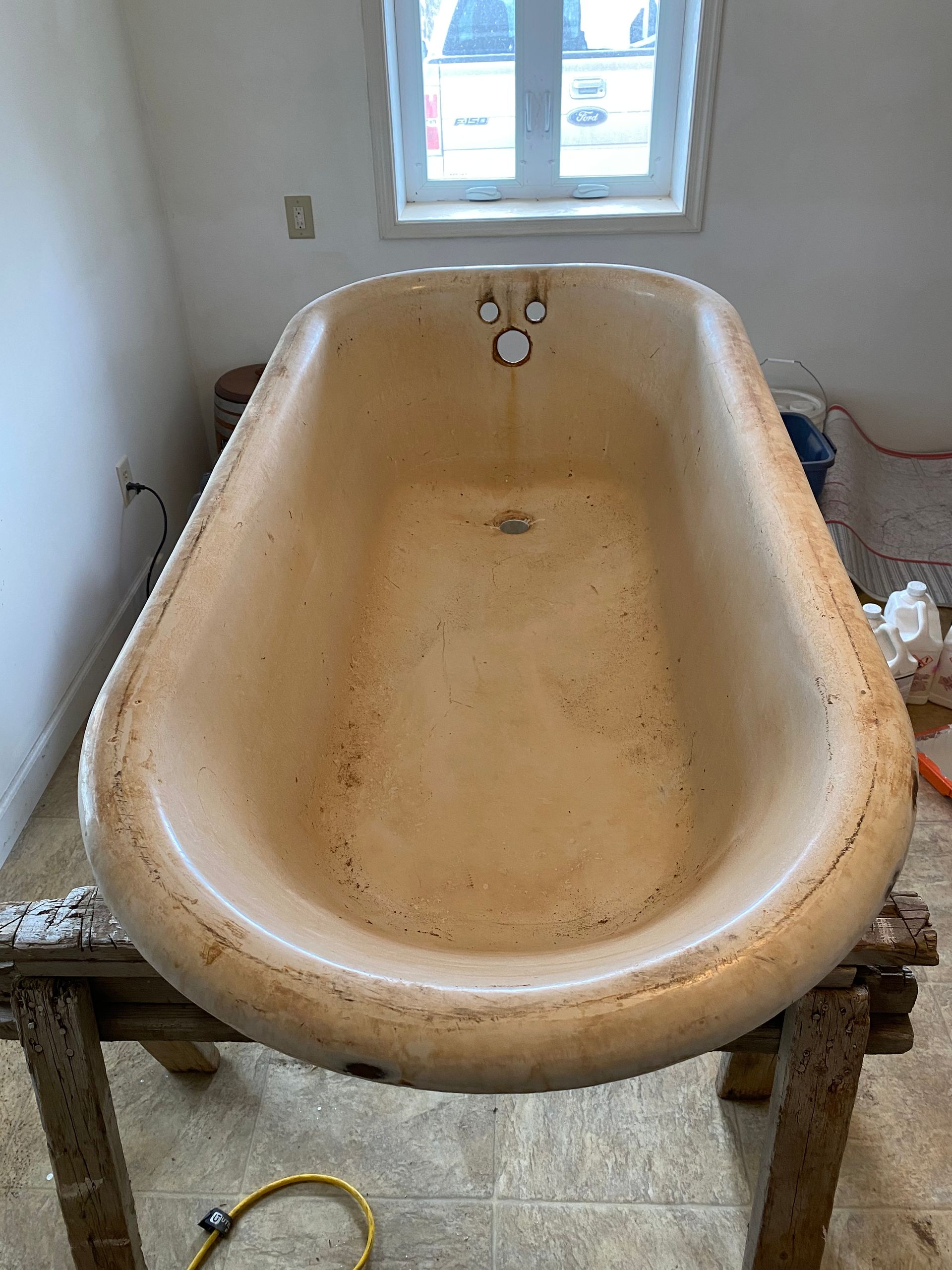 A bathtub is sitting on top of a wooden table in a bathroom