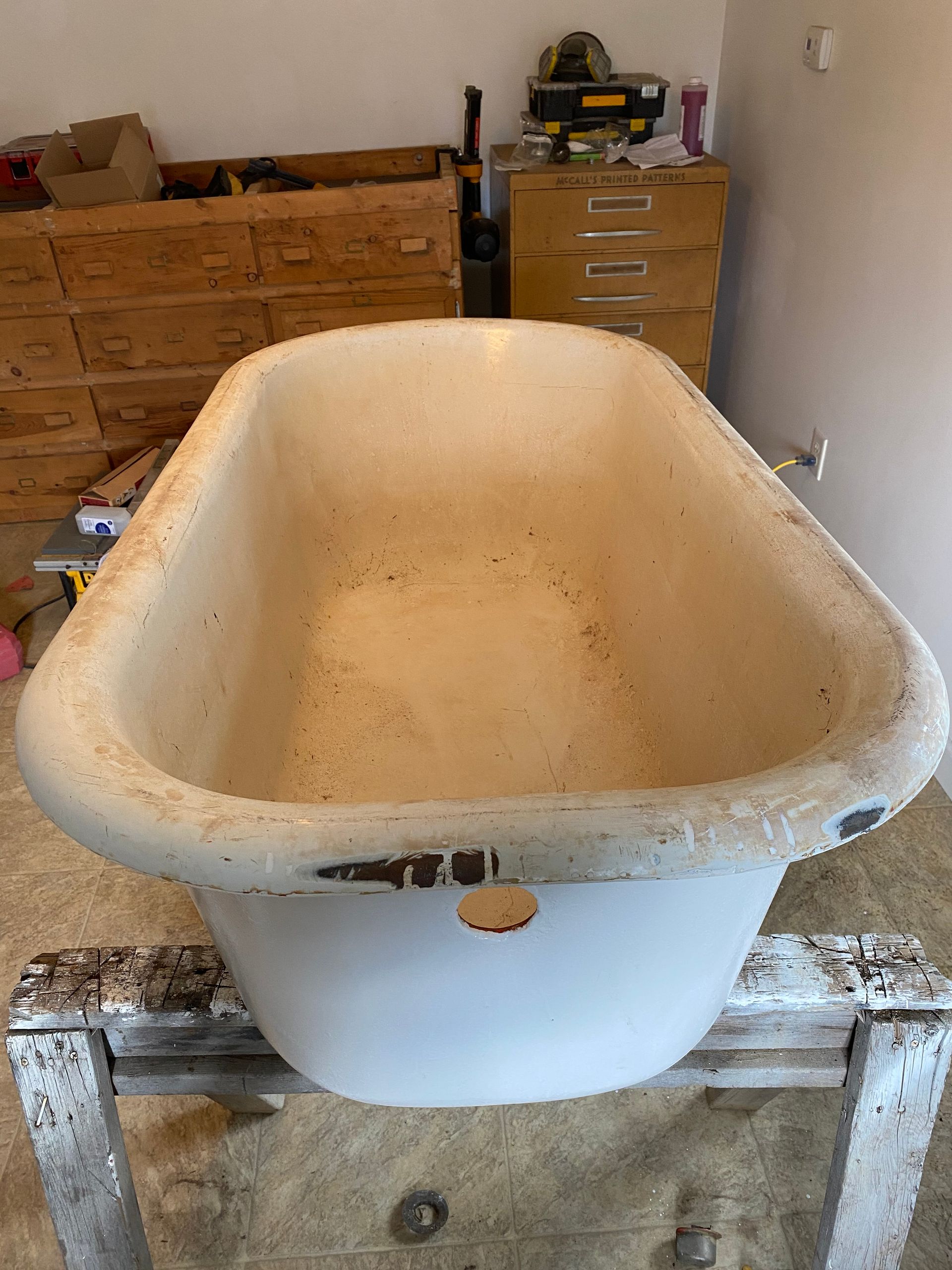 A white bathtub is sitting on top of a wooden table in a room