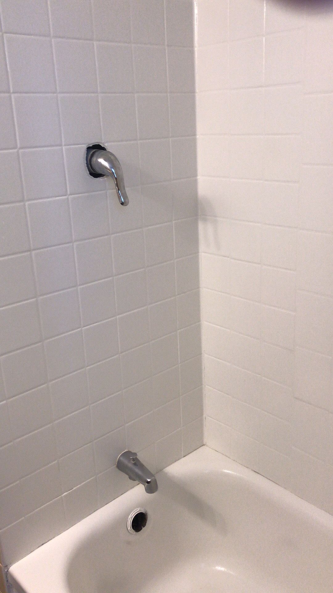 A bathtub in a bathroom with white tiles and a shower head