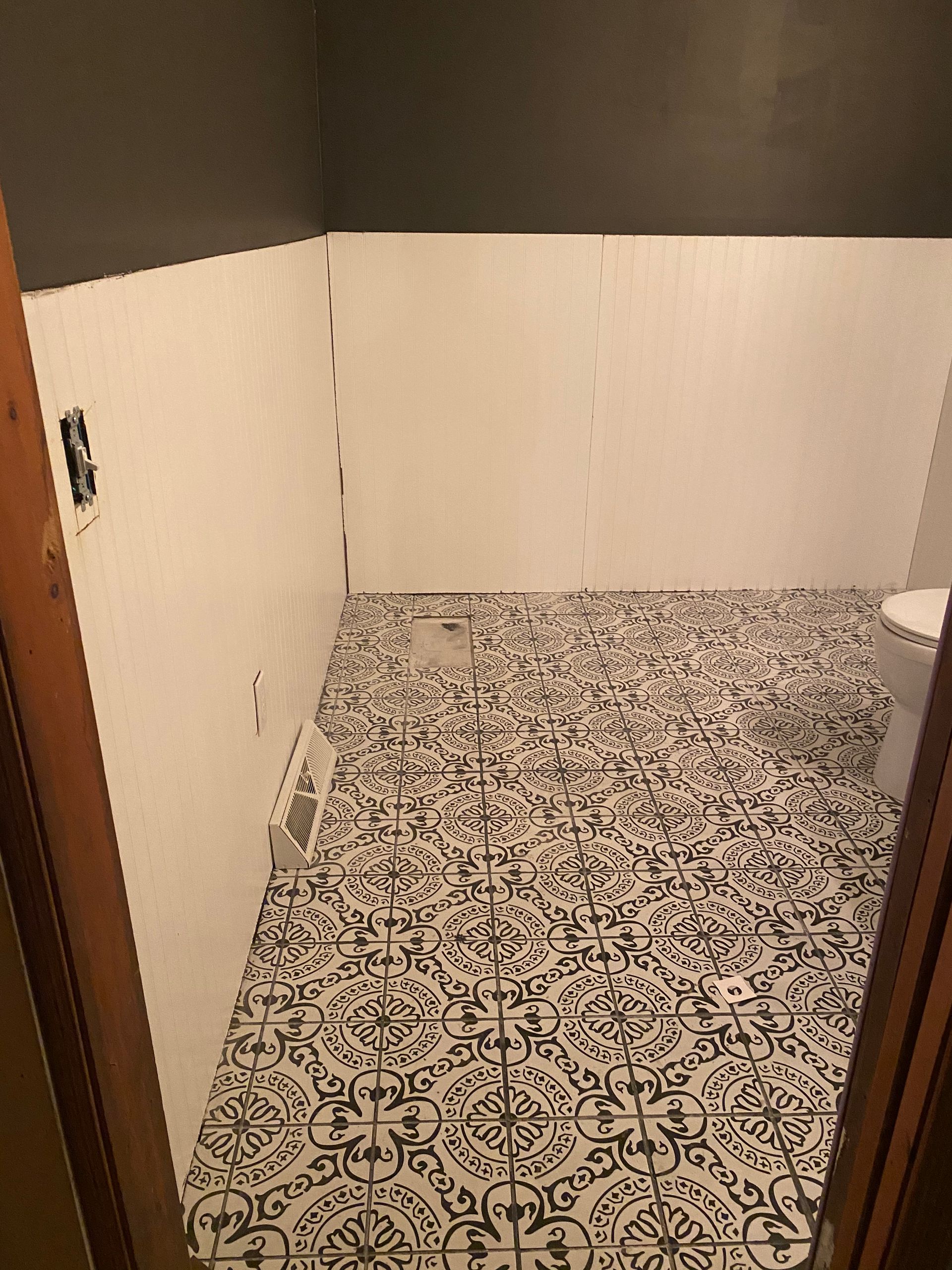 A bathroom with a toilet and a black and white tile floor