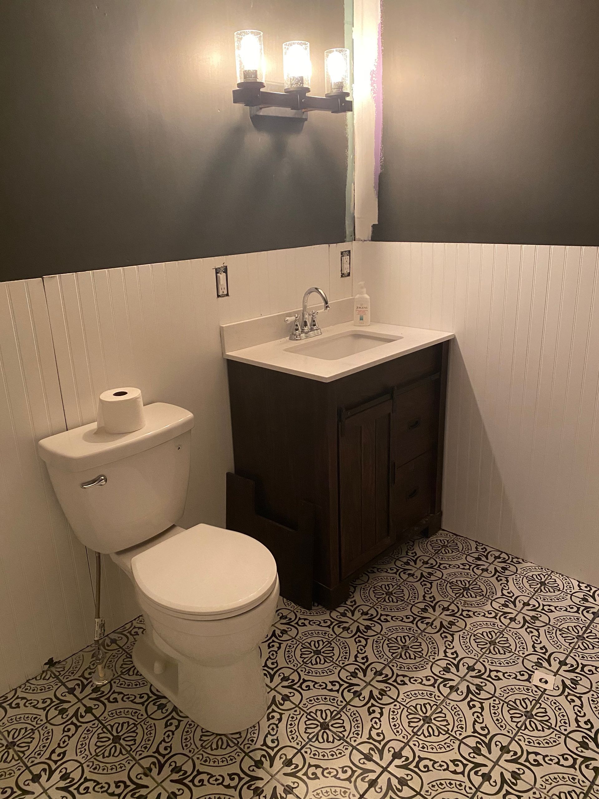 A bathroom with a toilet, sink and mirror