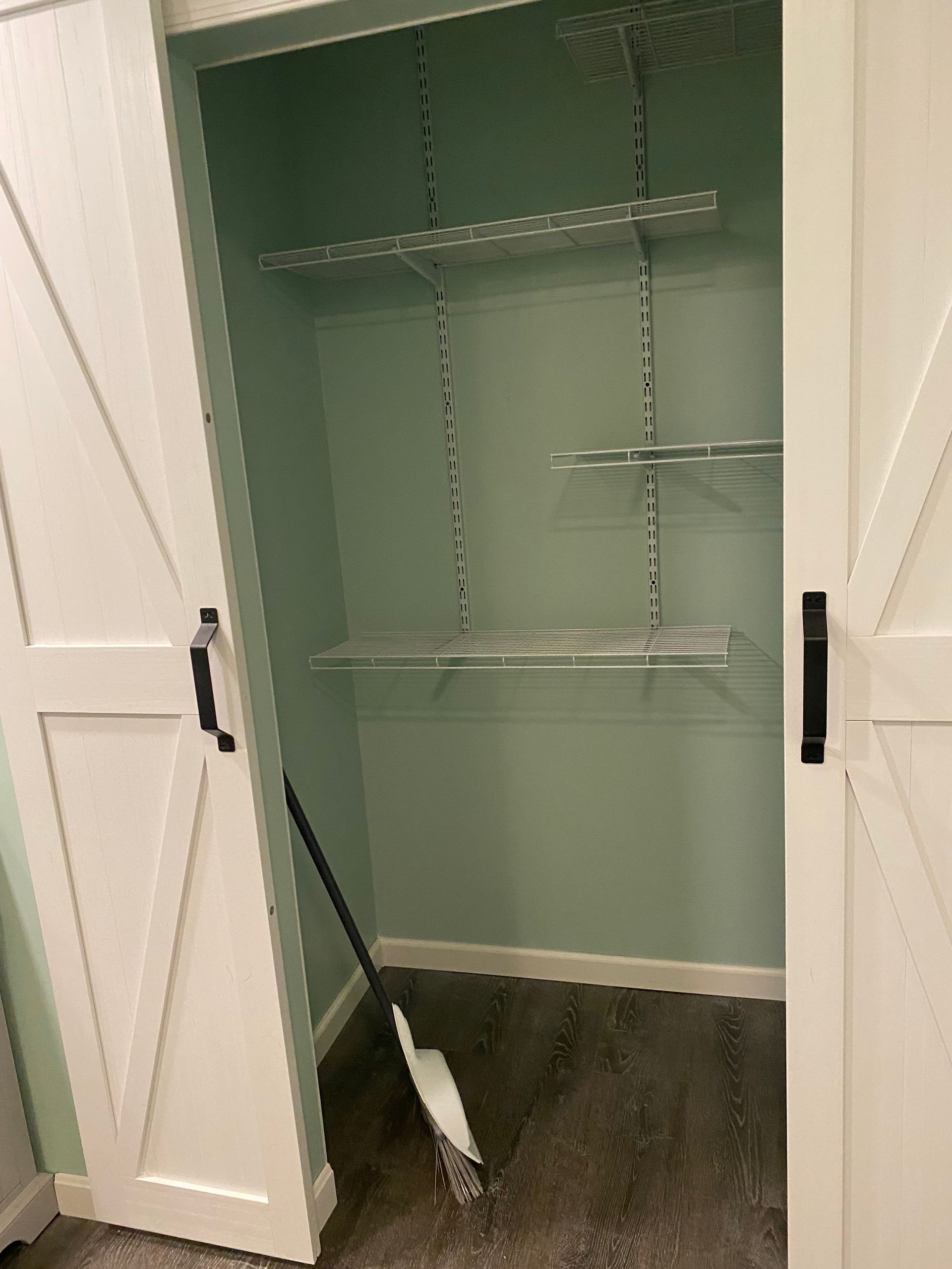 A closet with shelves and a mop in it .