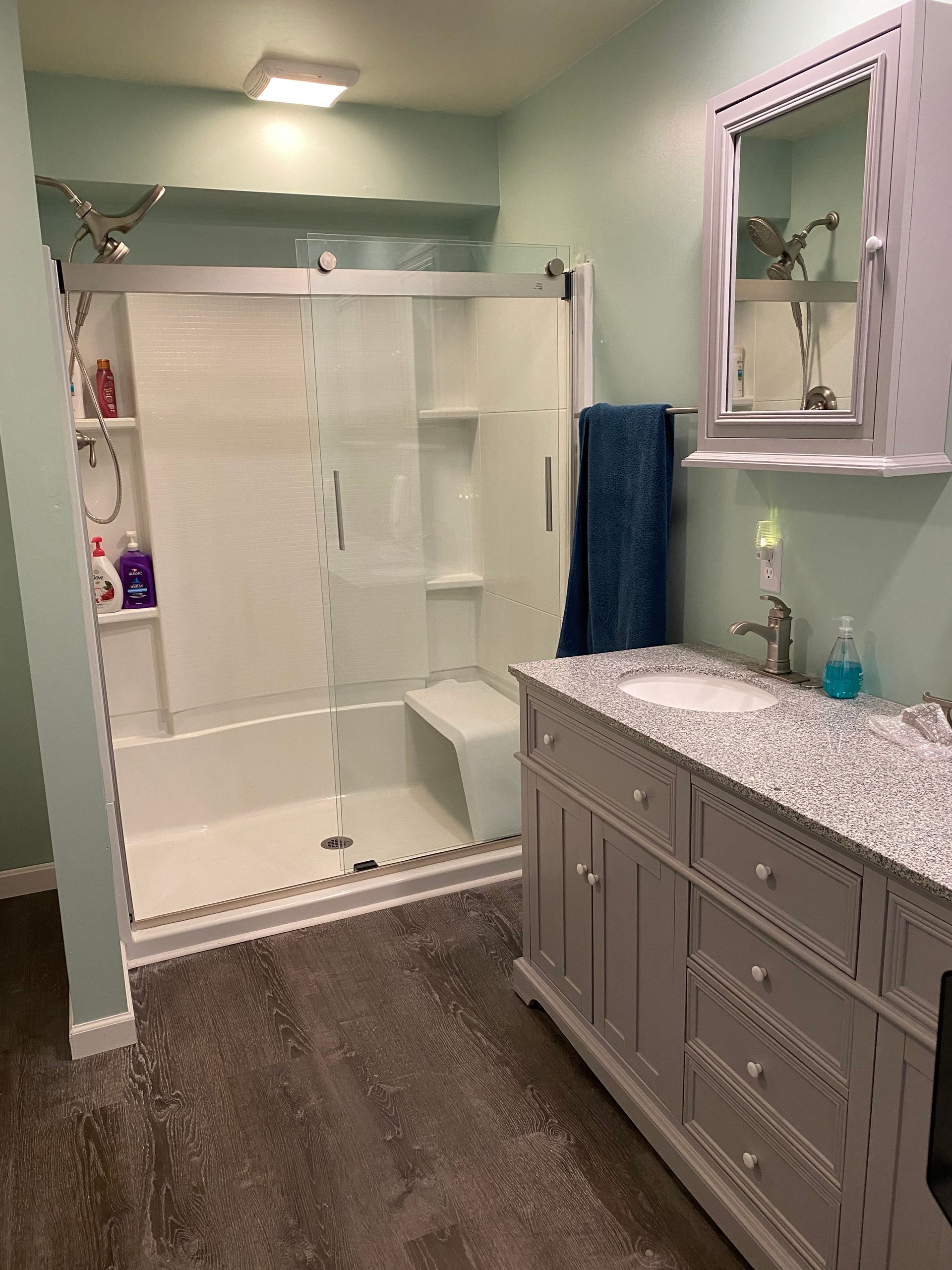 A bathroom with a sink, shower, and mirror