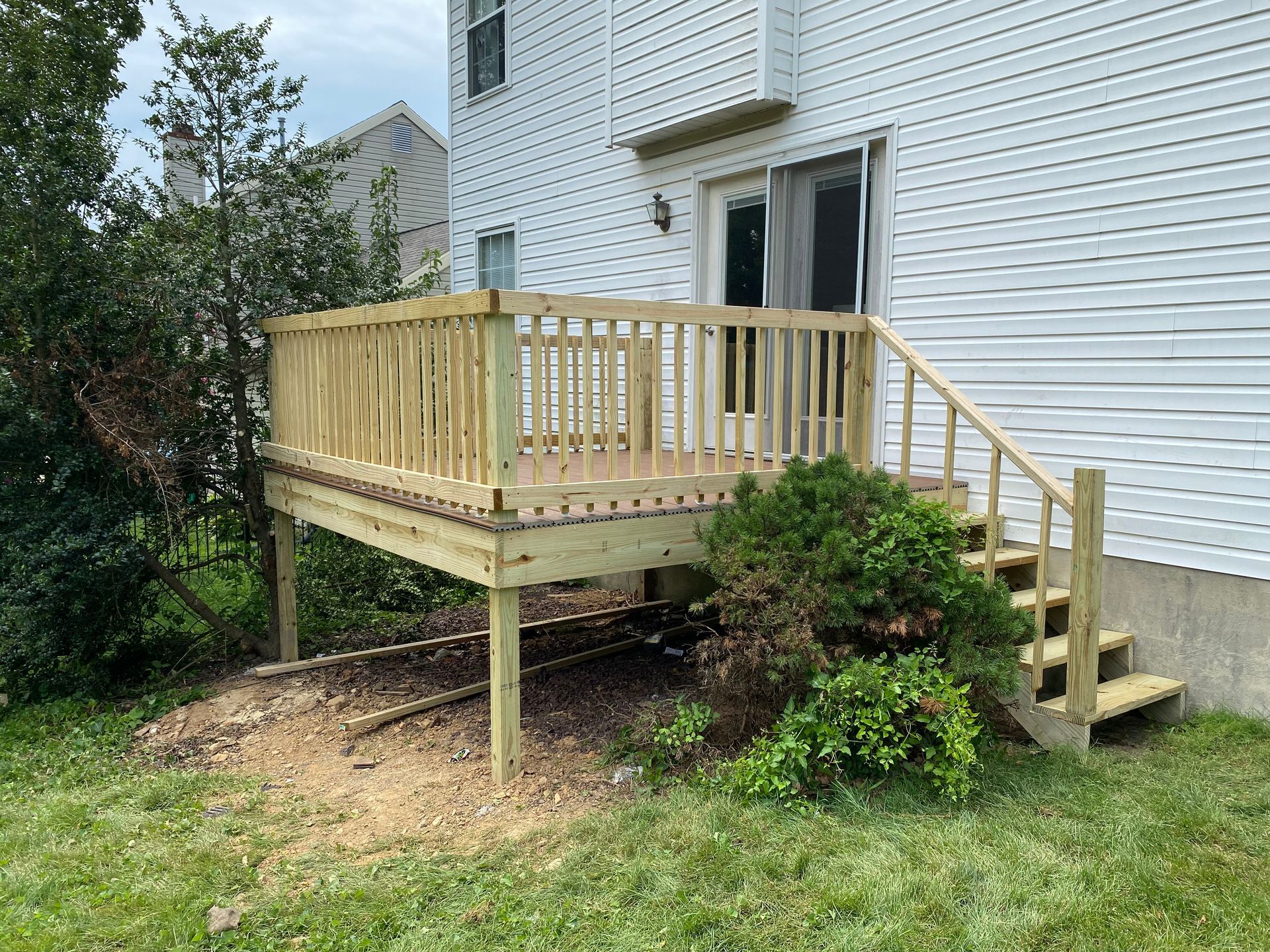 A wooden deck with stairs is in the backyard of a house
