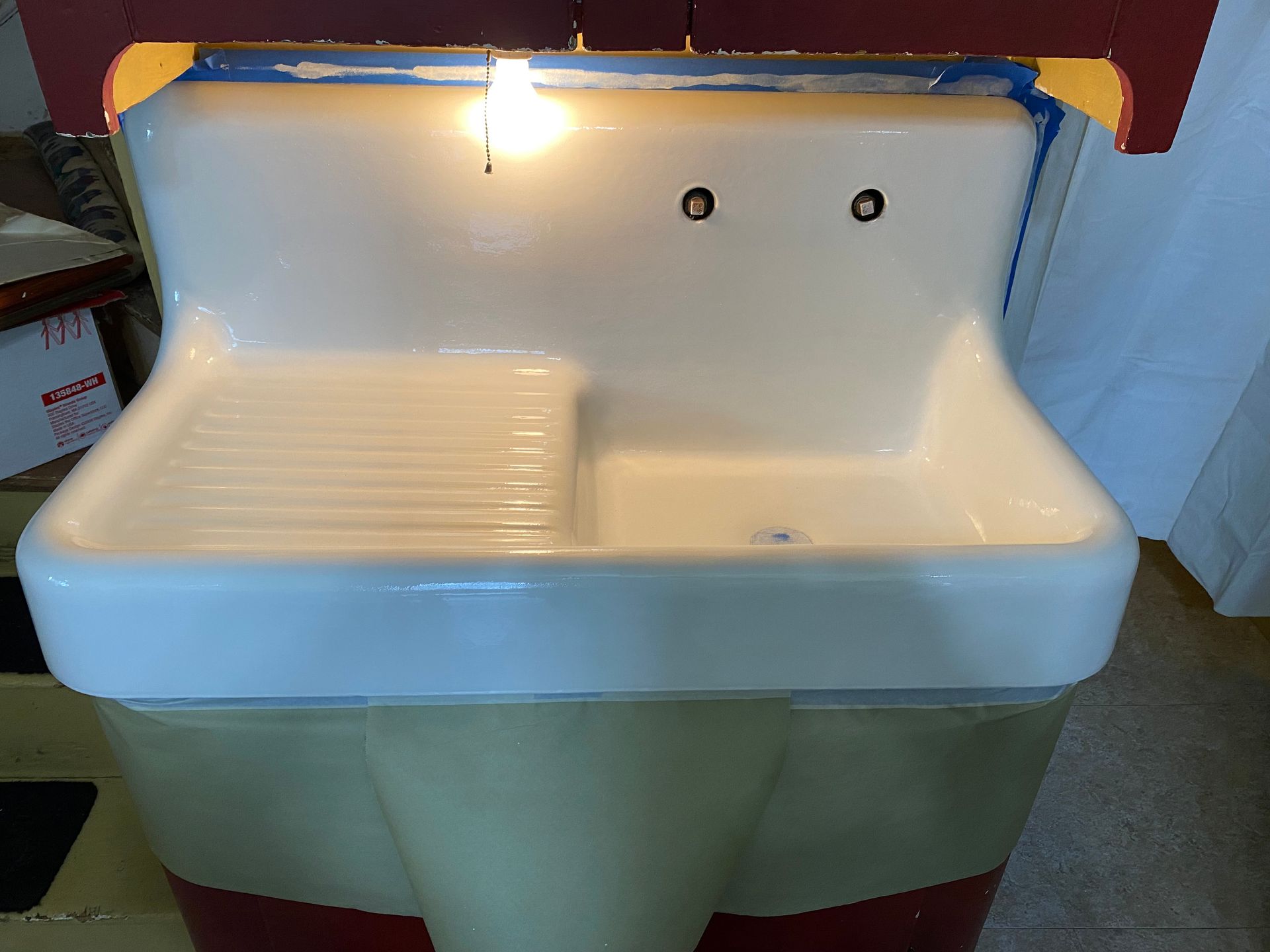 A white kitchen sink with a light on top of it