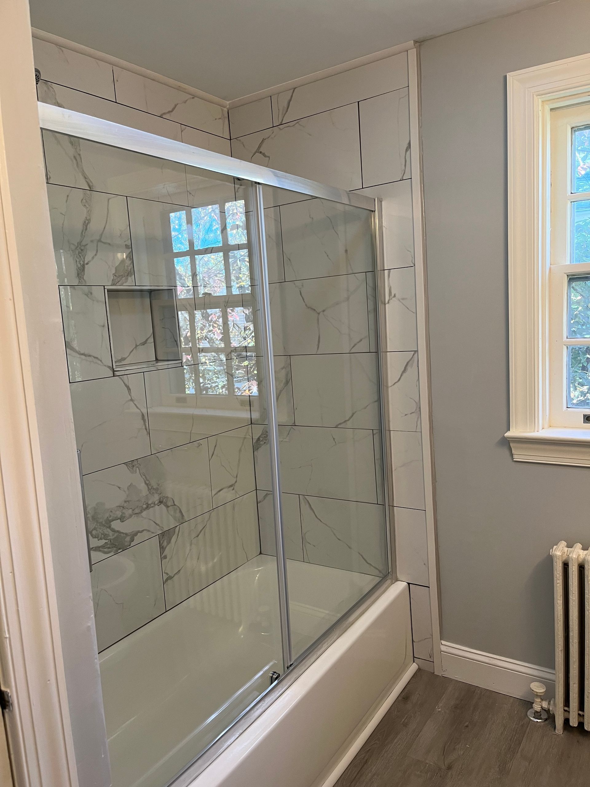 A bathroom with a tub and a shower with a glass door
