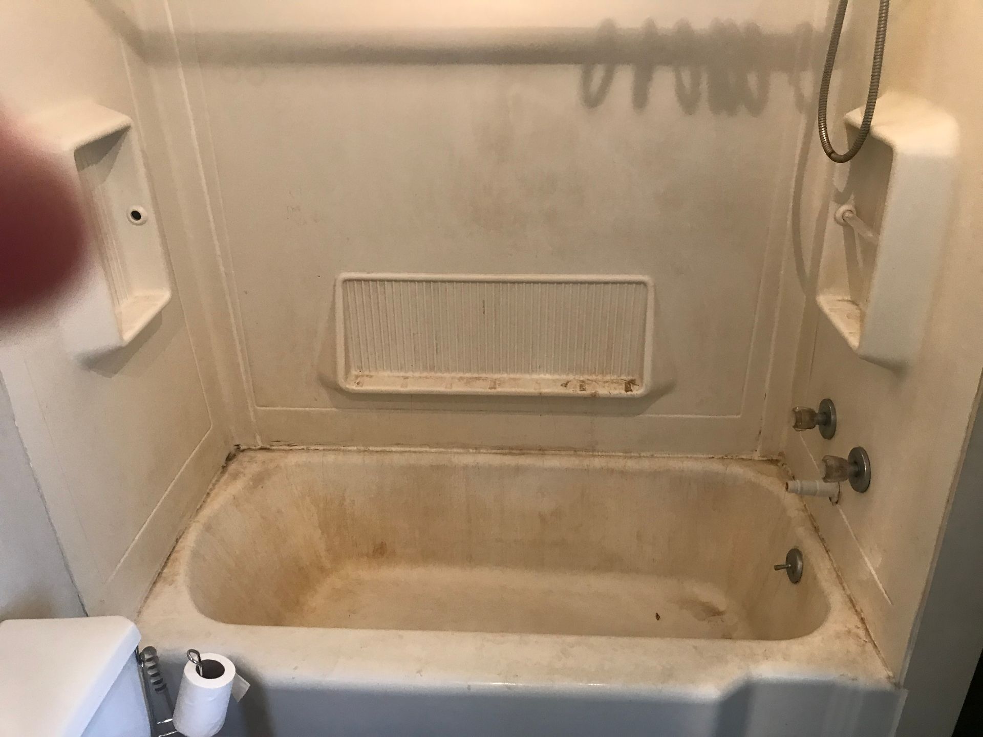 A dirty bathtub in a bathroom next to a toilet