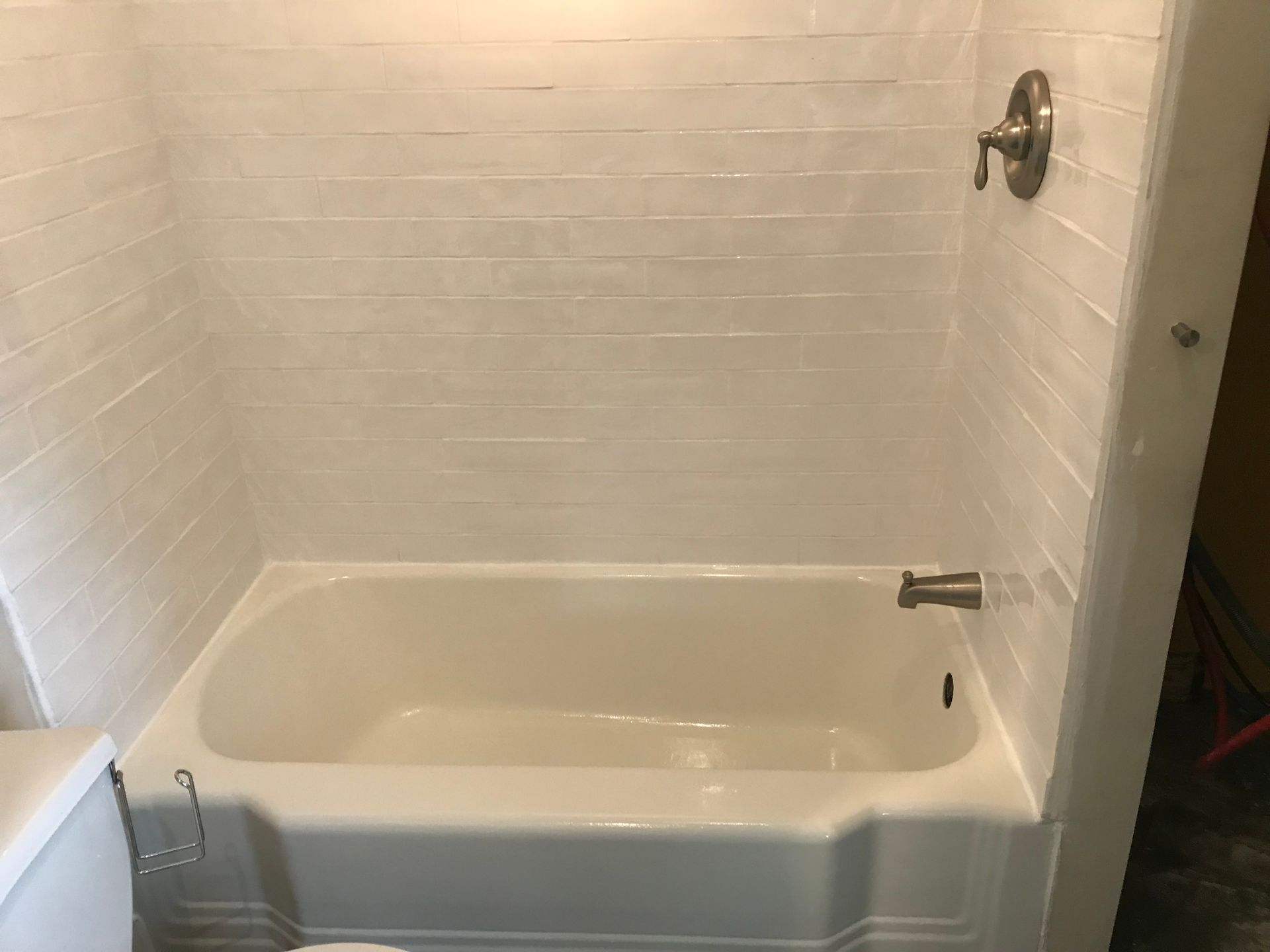 A white bathtub is sitting in a bathroom next to a toilet