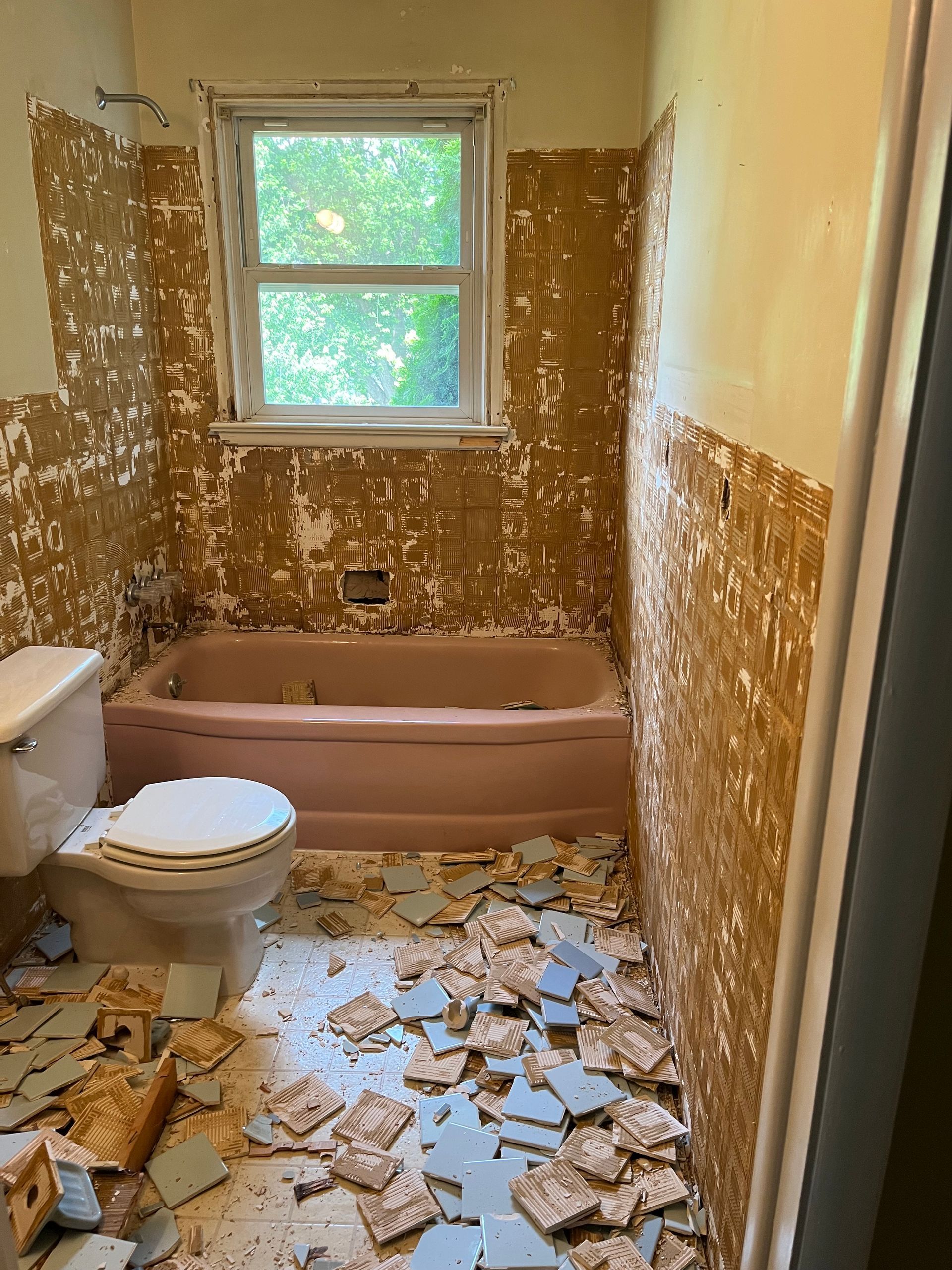 A bathroom with a toilet, bathtub and window is being remodeled