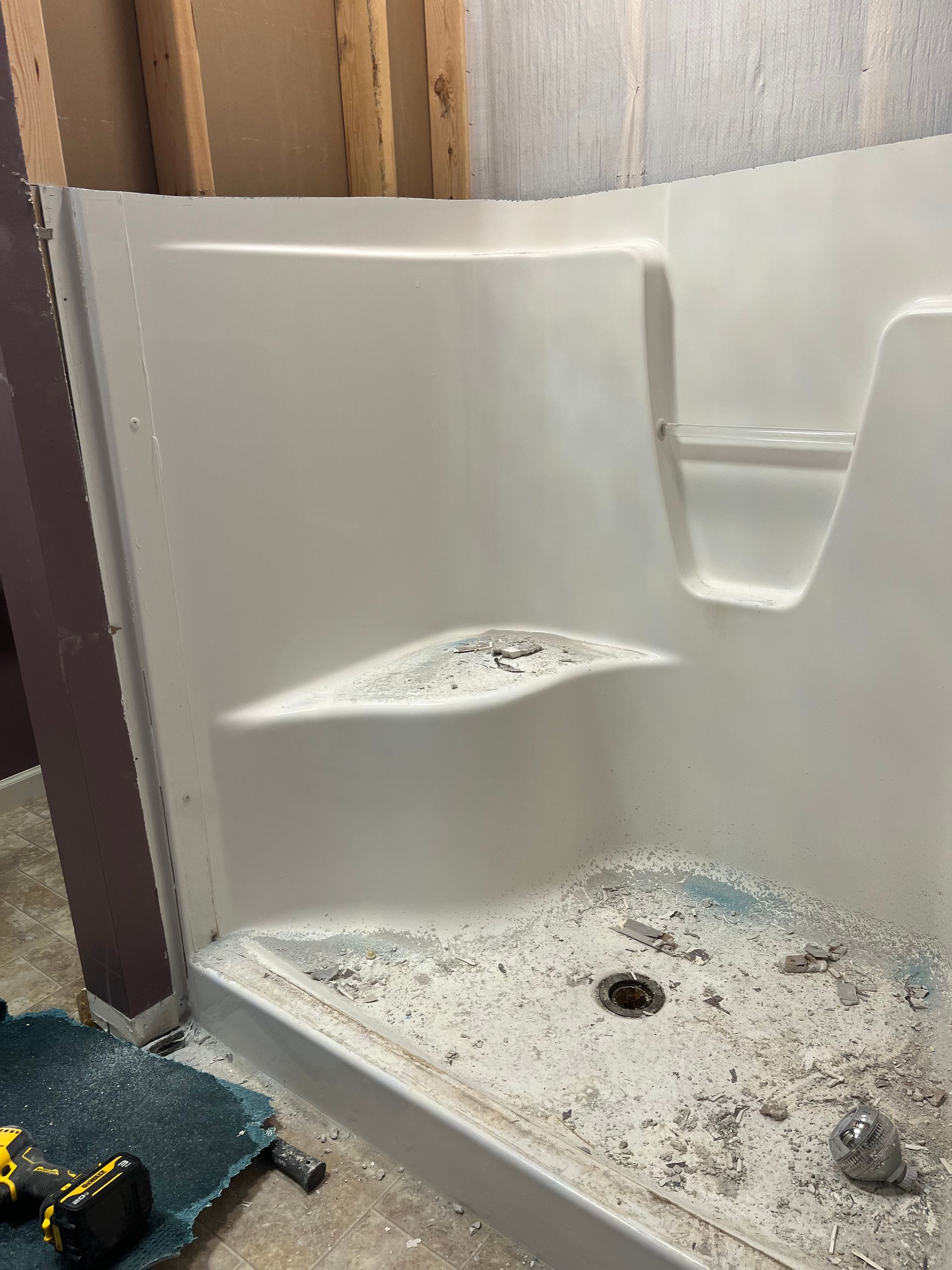 A white shower stall is being remodeled in a bathroom