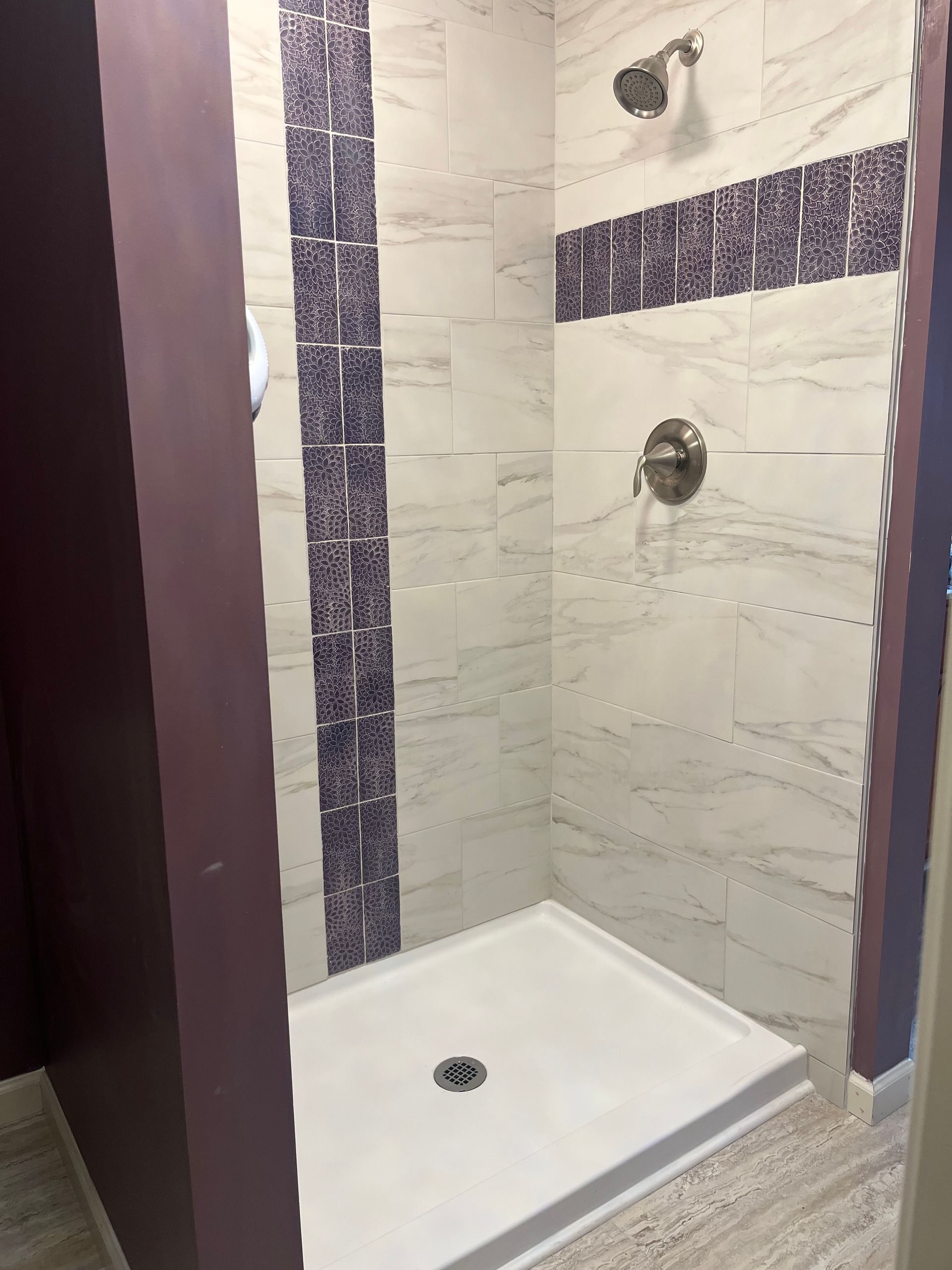 A bathroom with a walk in shower and a purple wall