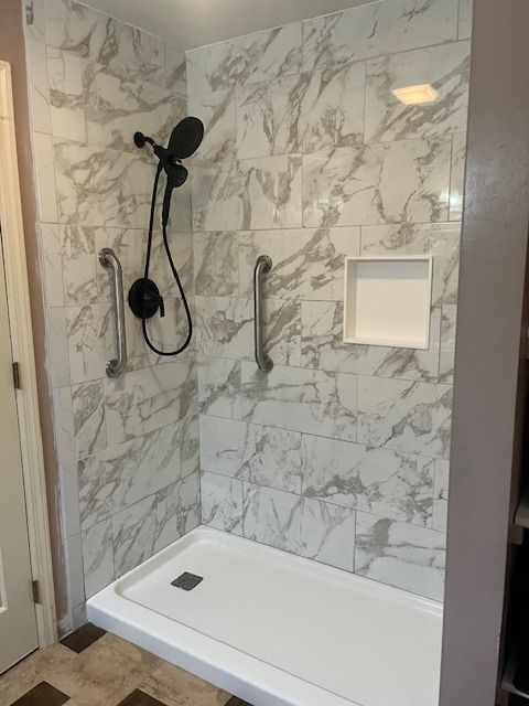 A bathroom with a walk in shower and a marble wall.