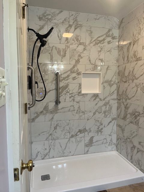 A bathroom with a walk in shower and a marble wall.