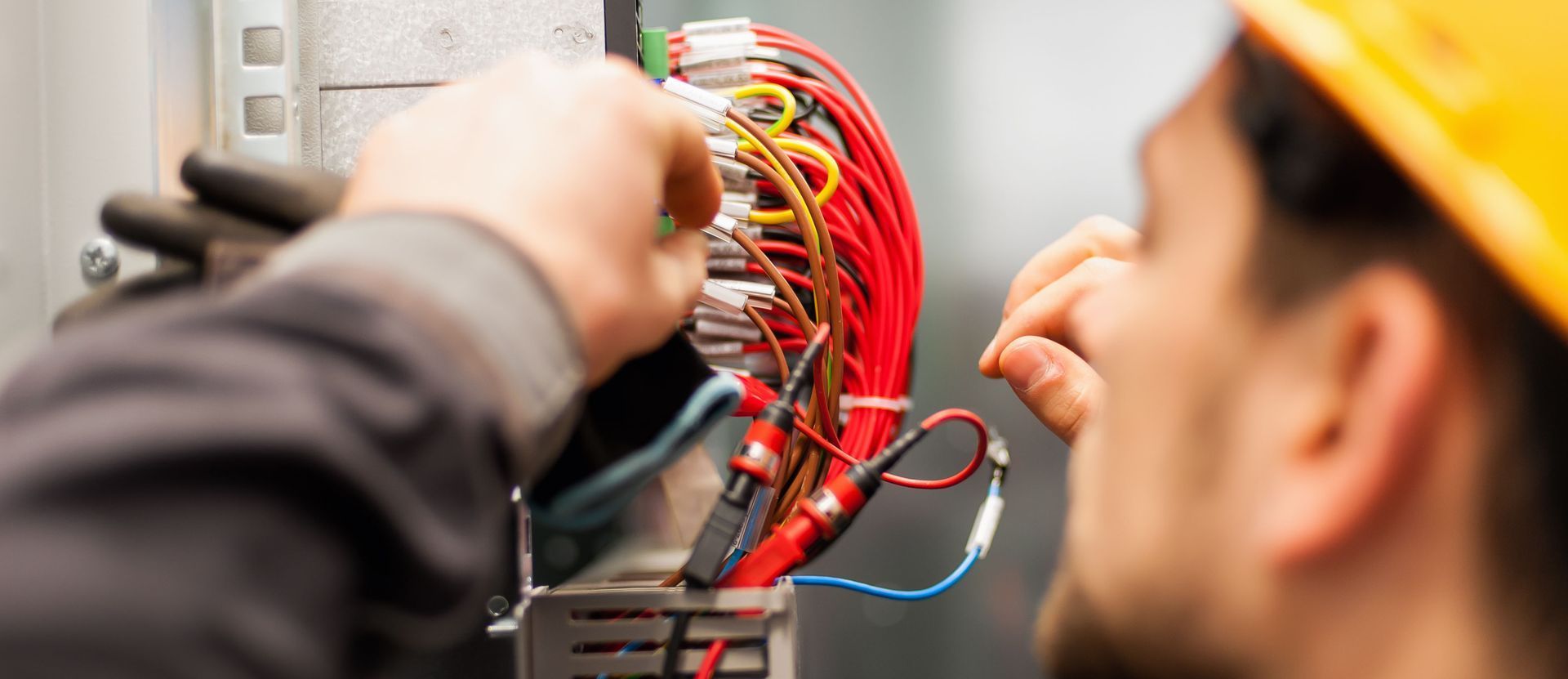 Technician wiring a red electrical panel in a workspace