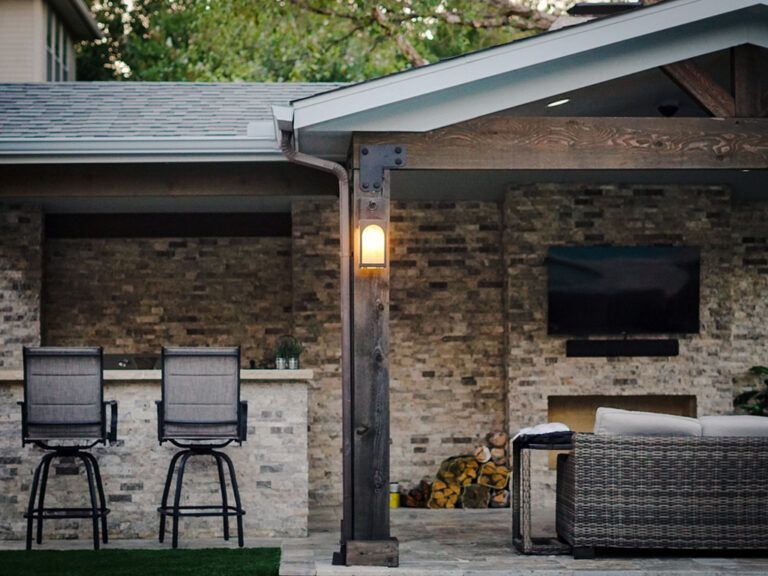 A patio with a bar , chairs , a couch and a television.