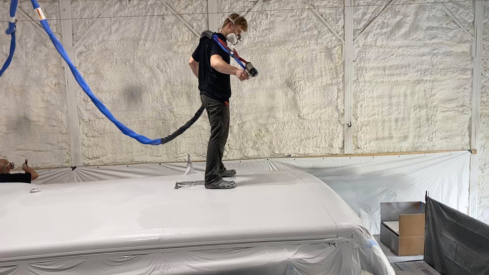 A man is spraying foam on the roof of a boat.