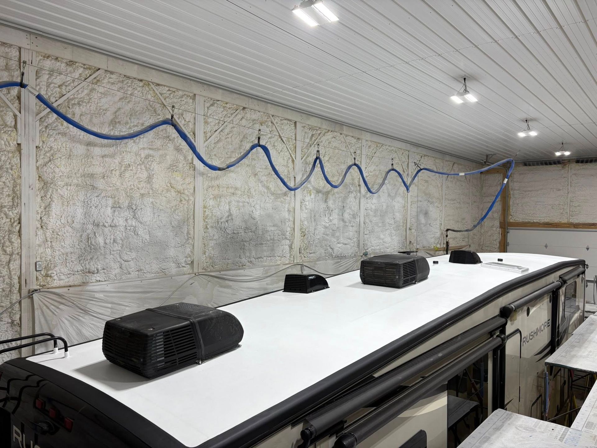 A rv is sitting in a garage with a white roof.