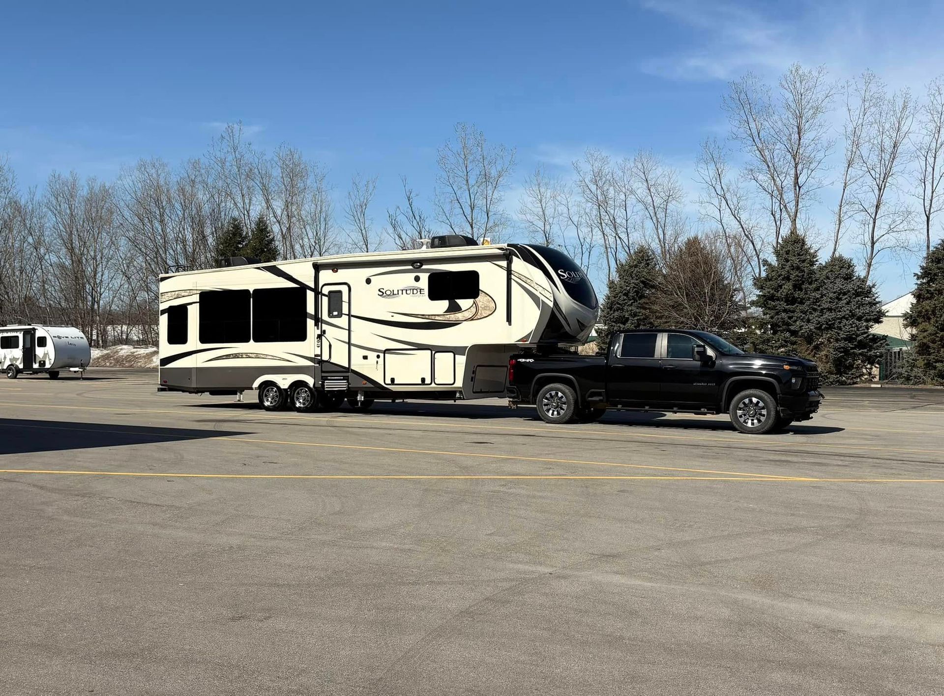 A truck is towing a trailer in a parking lot.