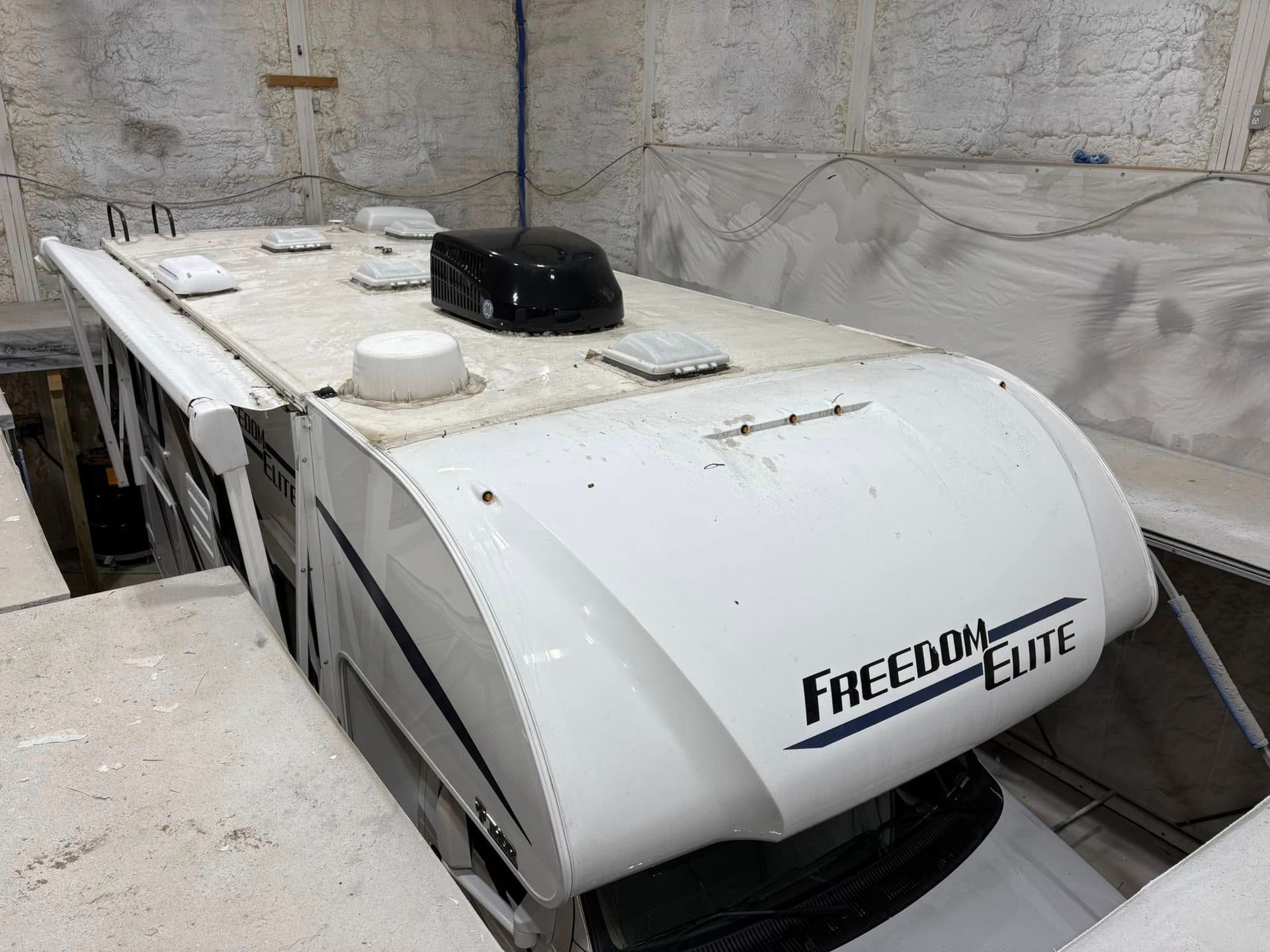 A white freedom elite camper is parked in a garage.