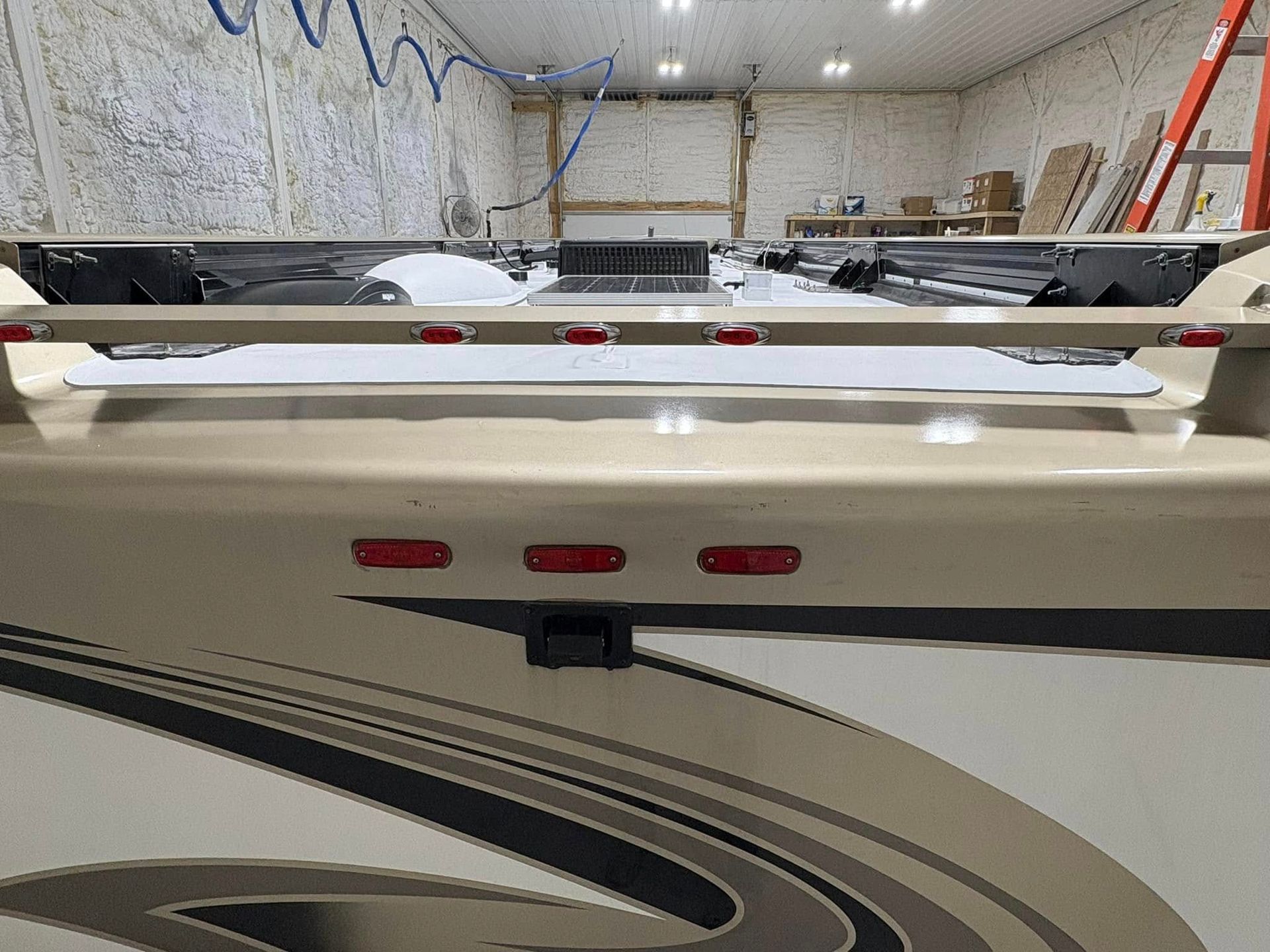 A rv is being built in a garage with a ladder in the background.