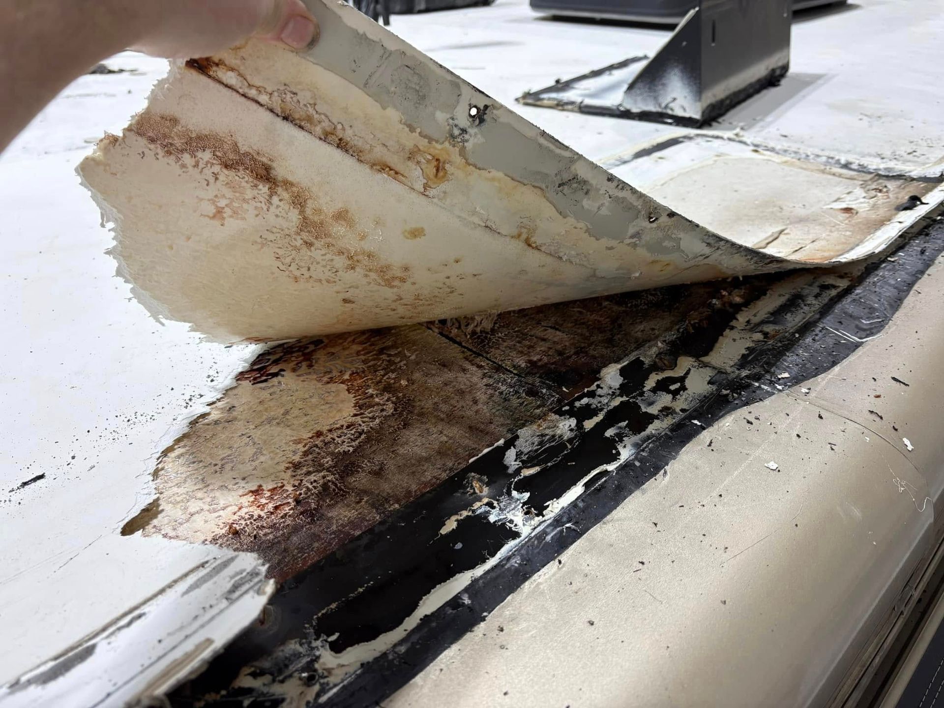 A person is holding a piece of paper on top of a roof.