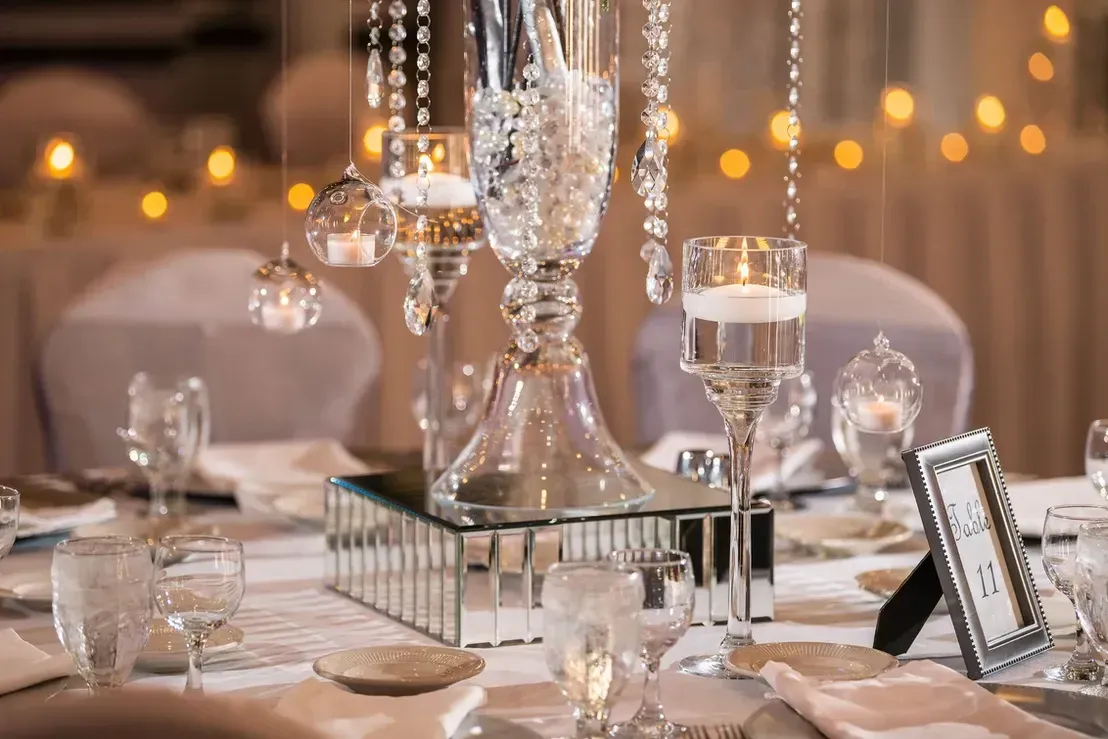 Elegant wedding table setting with crystal centerpiece, floating candles, and mirrored accents.