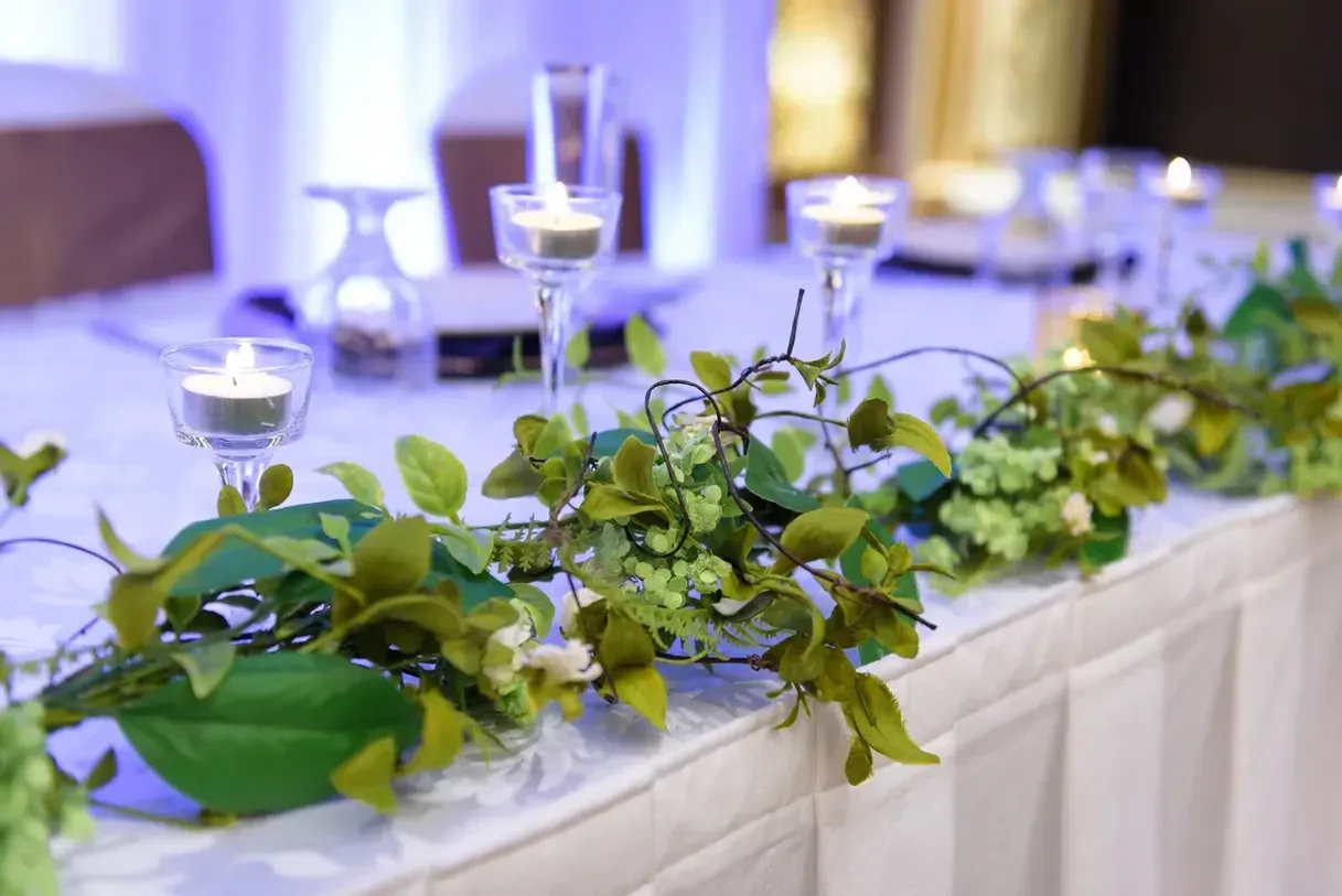 Wedding reception table with lit candles and greenery.