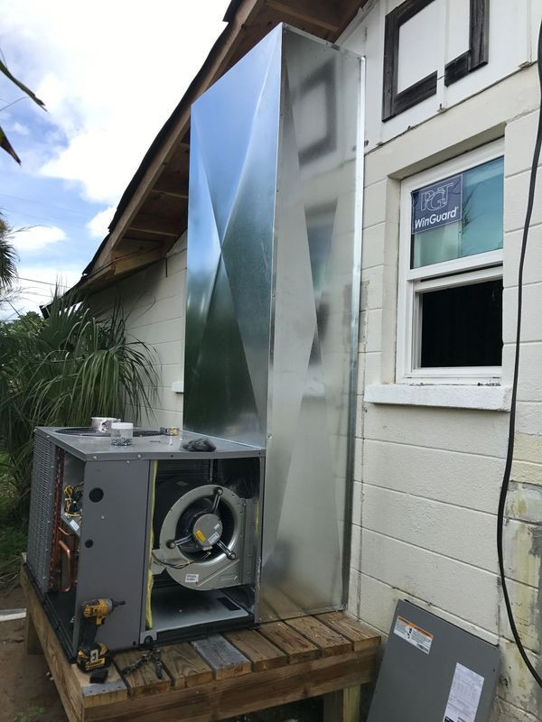 New HVAC unit installed outside a house with large metal vent.