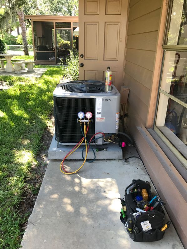 HVAC unit outside a building, with gauges attached. A toolbox sits nearby on the ground.