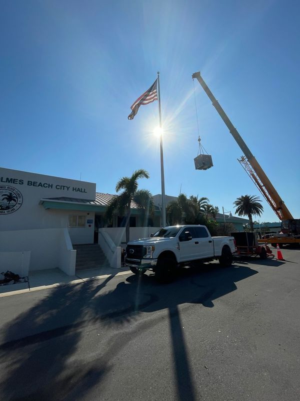Palm Beach City Hall with American flag, crane lifting object, white truck parked in front.