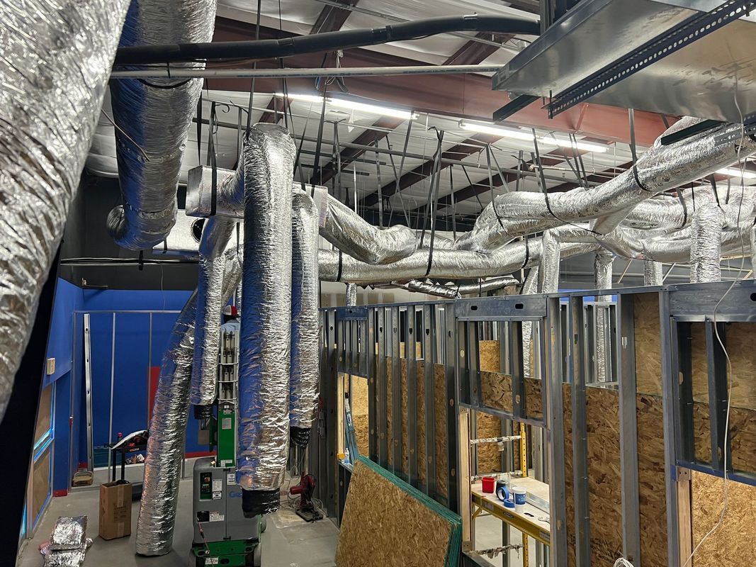 Interior view of construction site. Metal framing and ductwork are visible in the ceiling and walls.