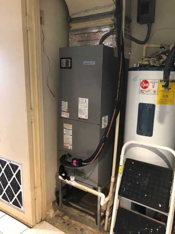HVAC unit and water heater in a basement. A stepladder is beside the water heater.
