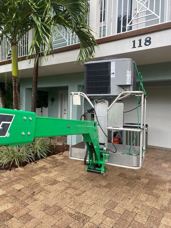 A green lift carrying an air conditioning unit to a building with the number 118.