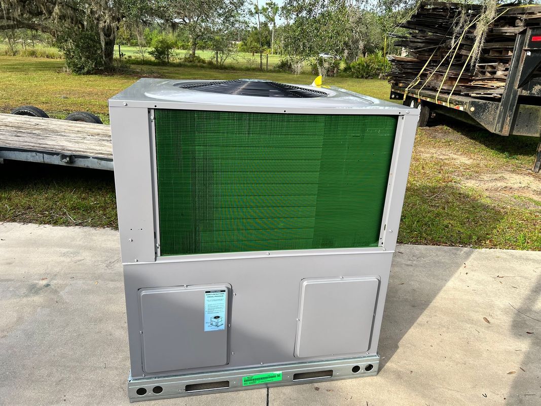 Gray HVAC unit with green cooling coils, outdoors on a sunny day.
