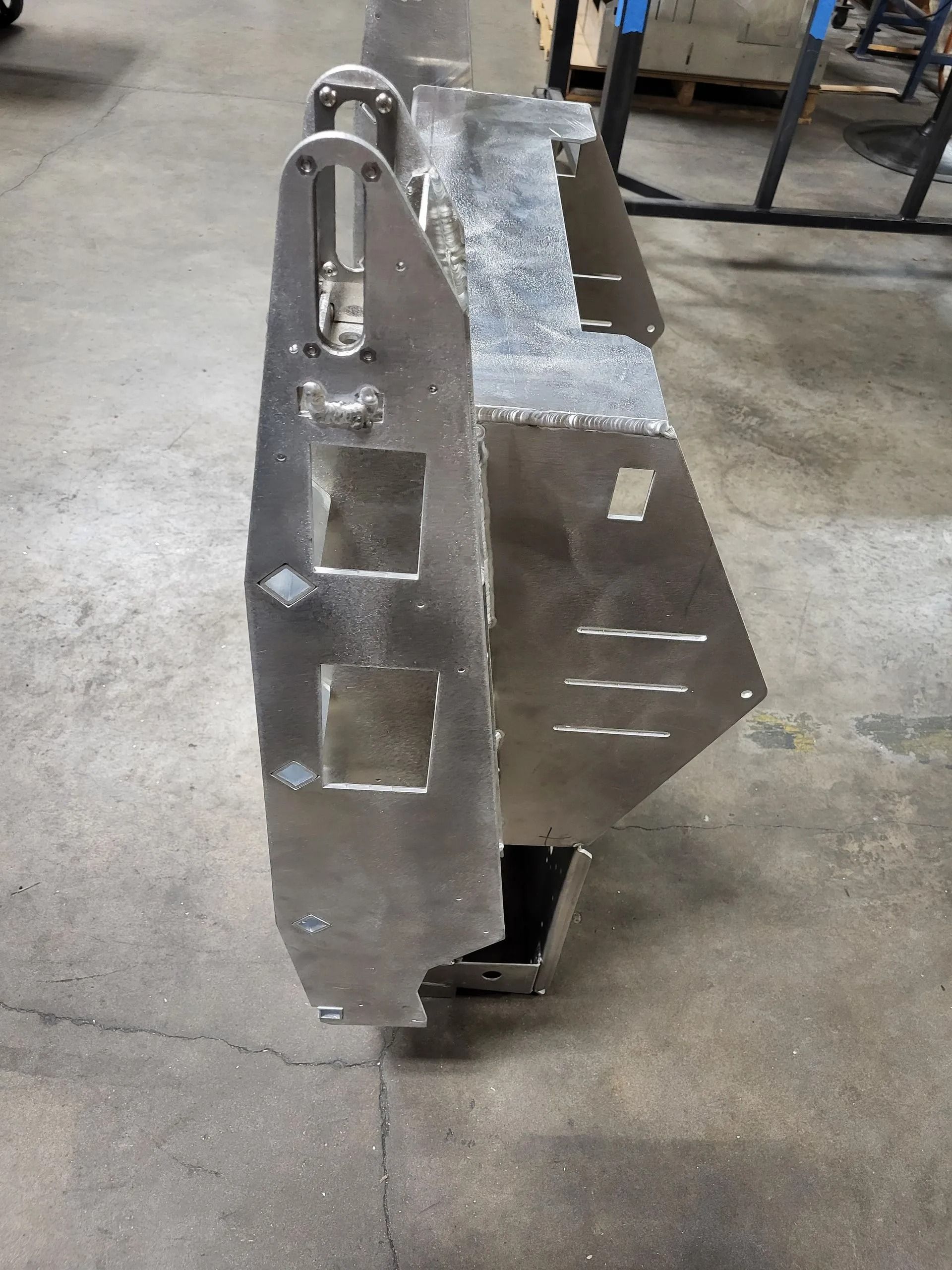 Steel fabricated bumper with square cutouts and mounting hardware.